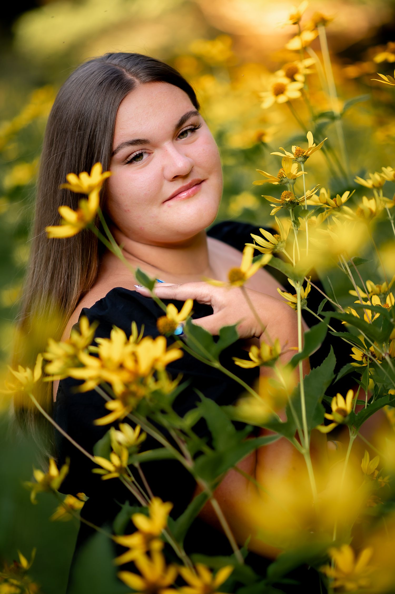 Portrait surrounded by vibrant yellow wildflowers in golden sunset light.