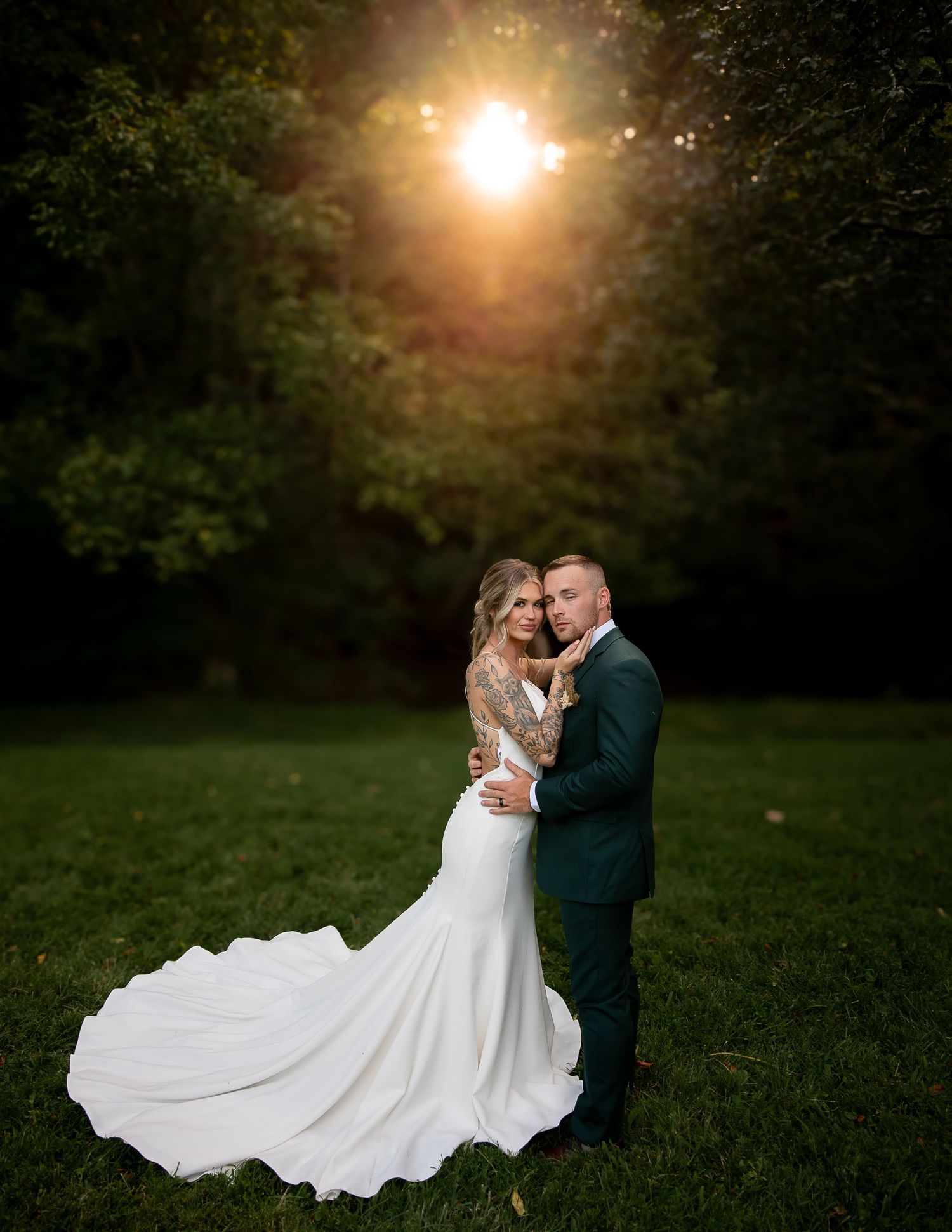 A couple shares a romantic moment at sunset in a lush garden setting with the bride's white dress flowing elegantly.