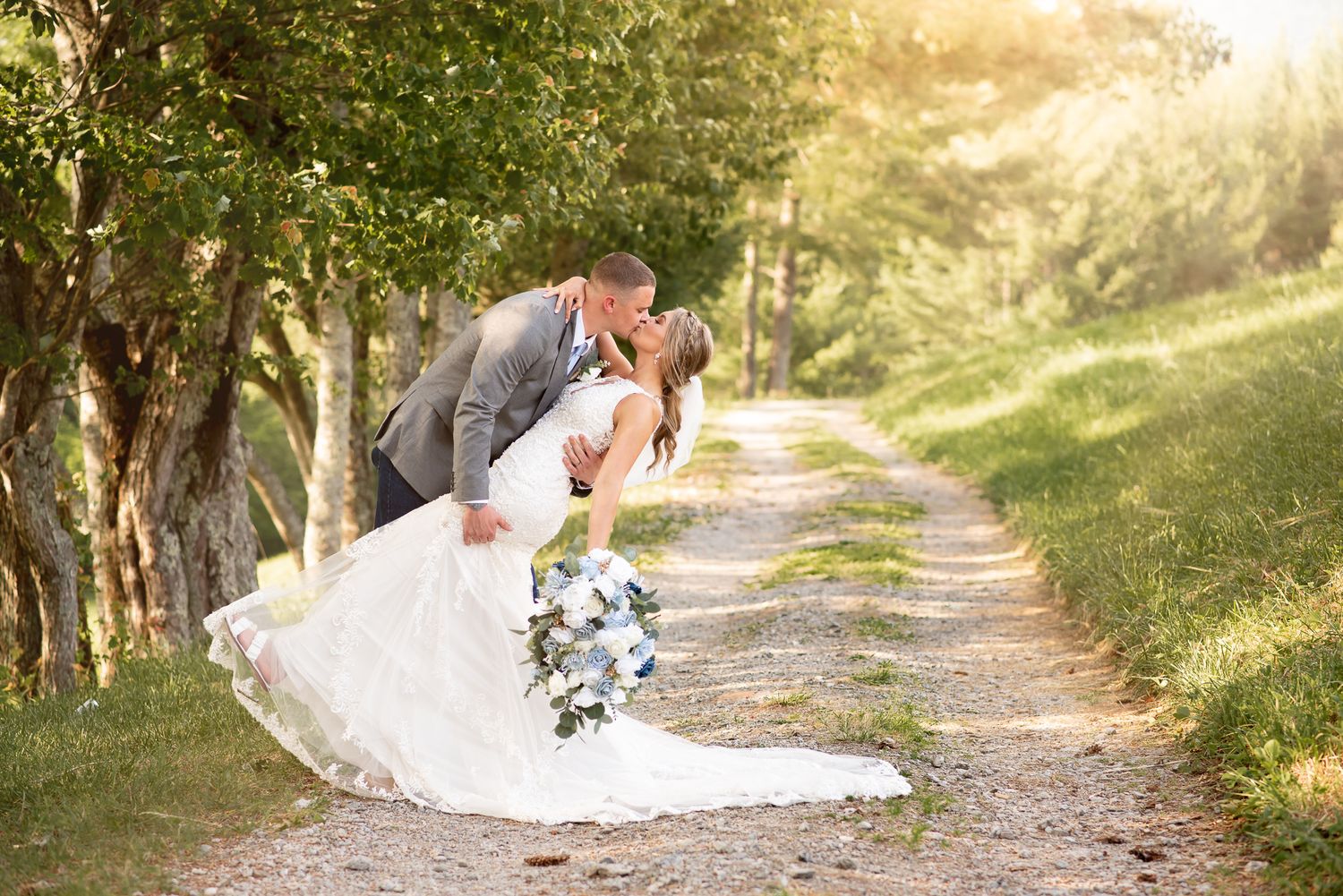Wedding couple shares a playful moment on a tree-lined path during golden hour.