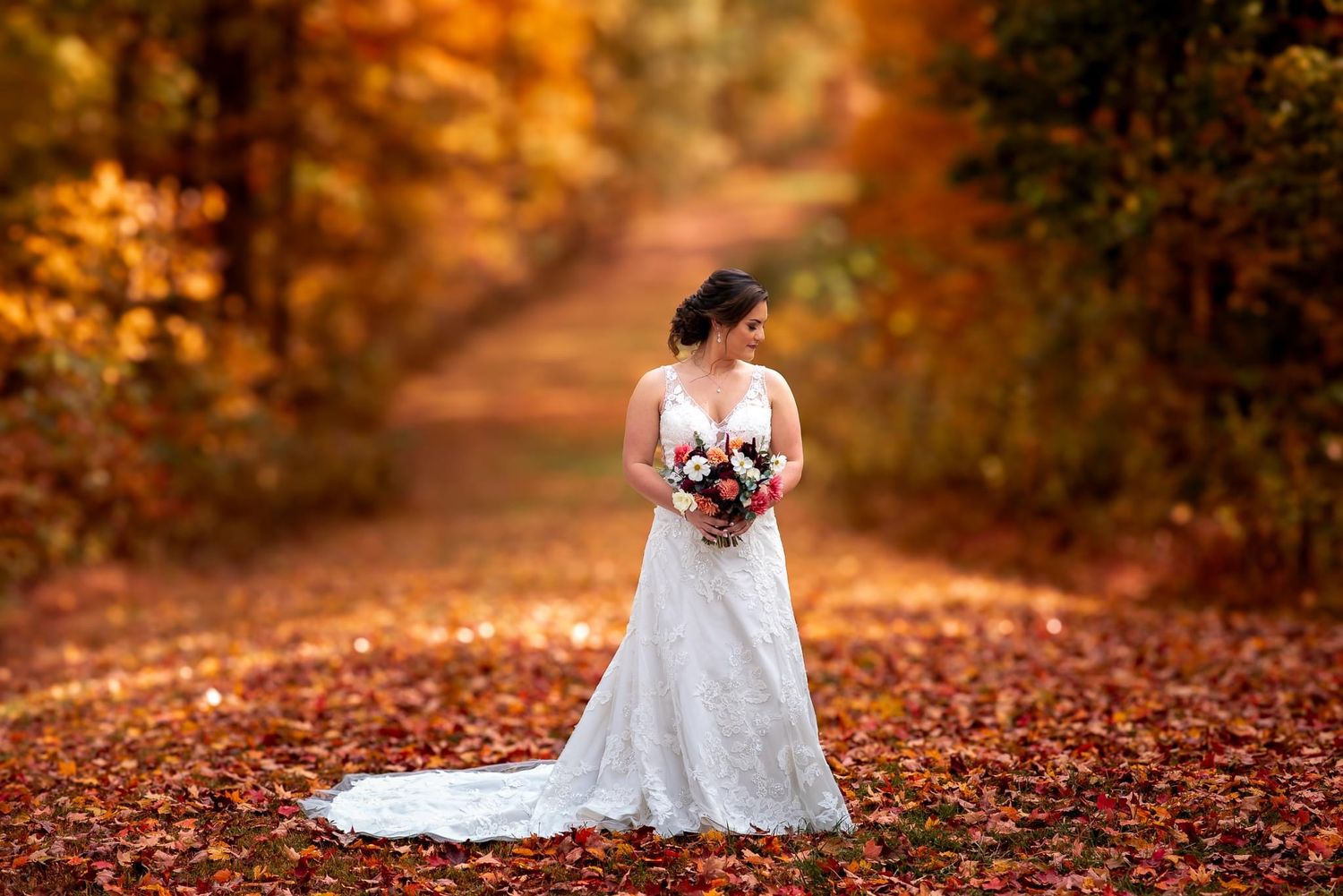 A bridal portrait on a path covered in fall leaves with rich autumn colors.