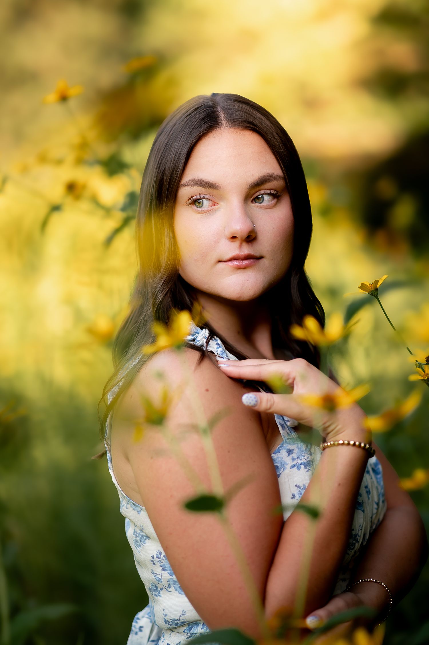 Portrait photograph in a natural setting with yellow wildflowers and soft golden sunlight creating a dreamy summer mood.