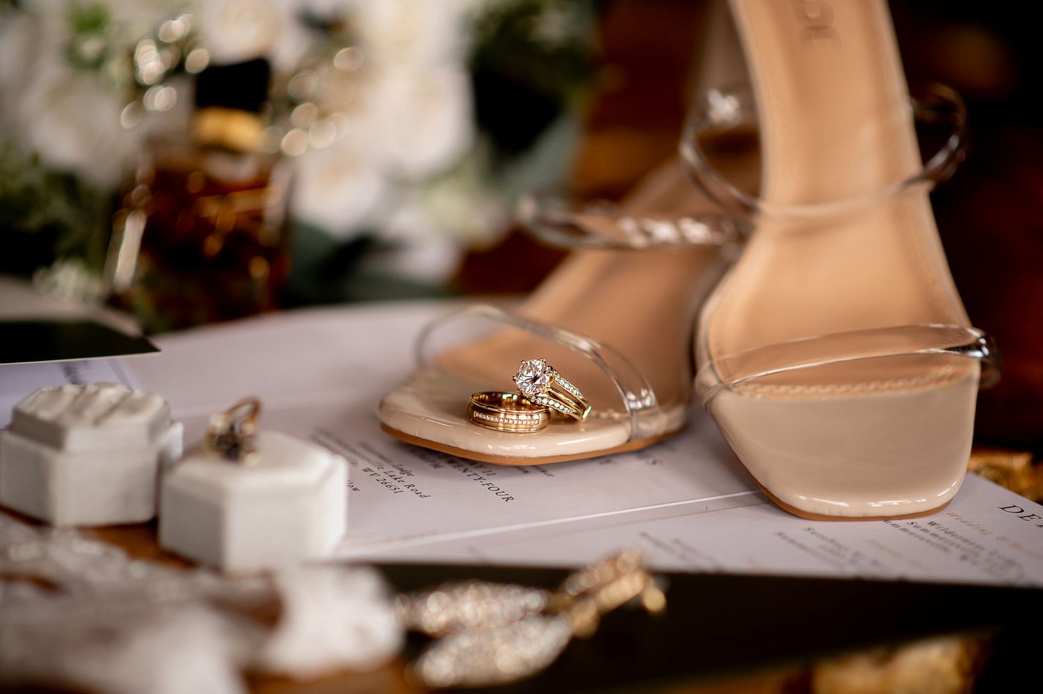 Elegant wedding accessories including bridal shoes and jewelry displayed on white surface.