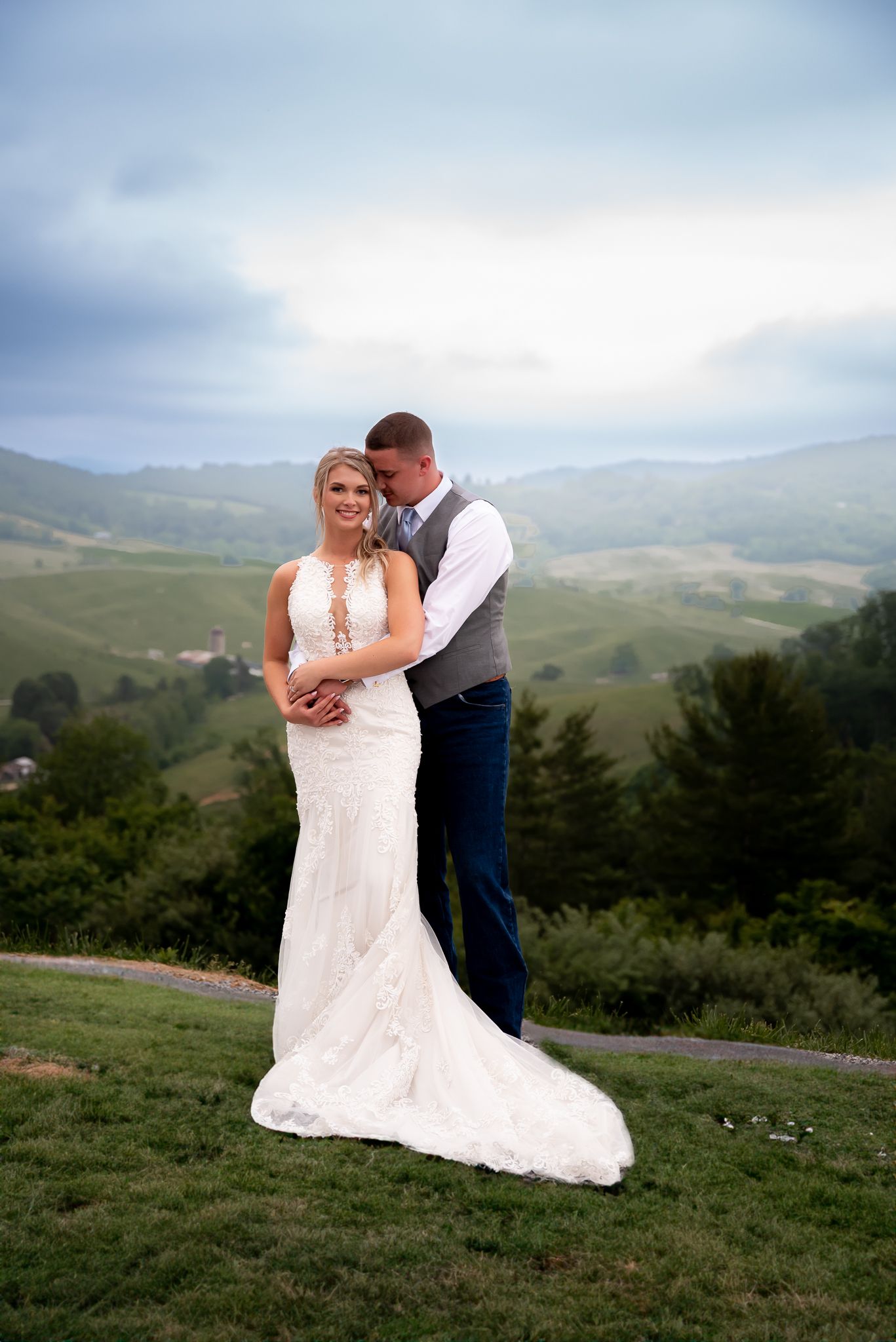 Elegant wedding portrait featuring a couple in formal attire against a misty mountain landscape.