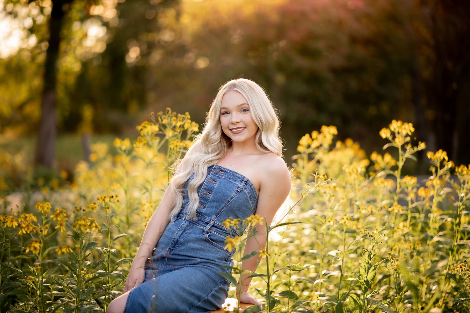 Portrait in a field of yellow wildflowers at sunset with denim overalls creating a casual country aesthetic.