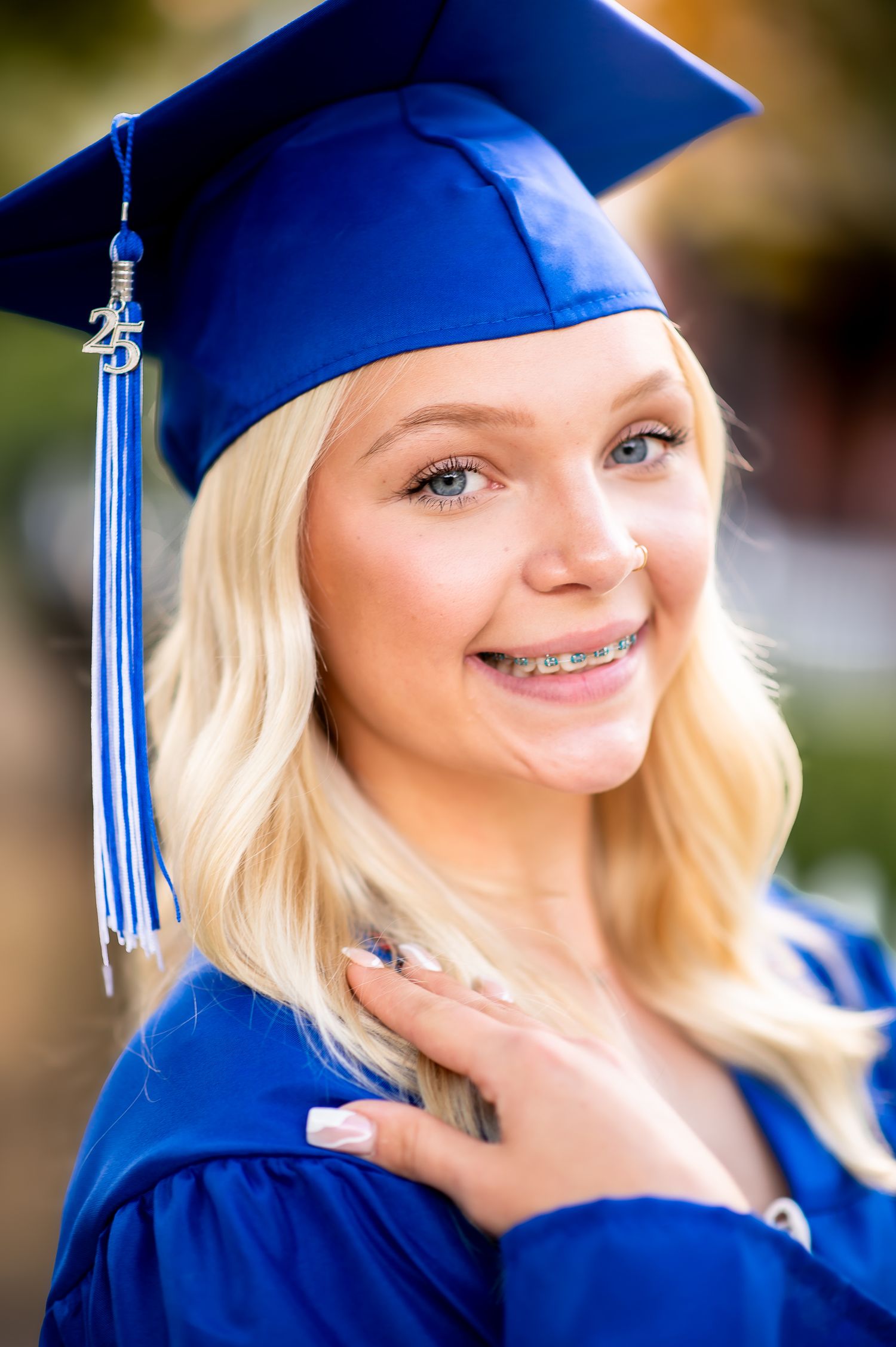 A graduation portrait featuring a student in blue cap and gown with tassel.