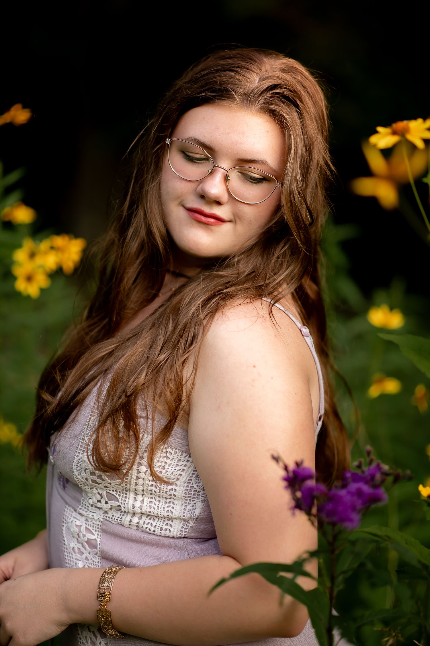 Dreamy summer portrait among yellow flowers wearing white lace and glasses.