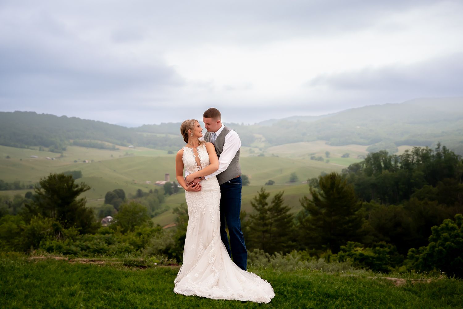 Wedding photos taken against a scenic mountain landscape with rolling hills.