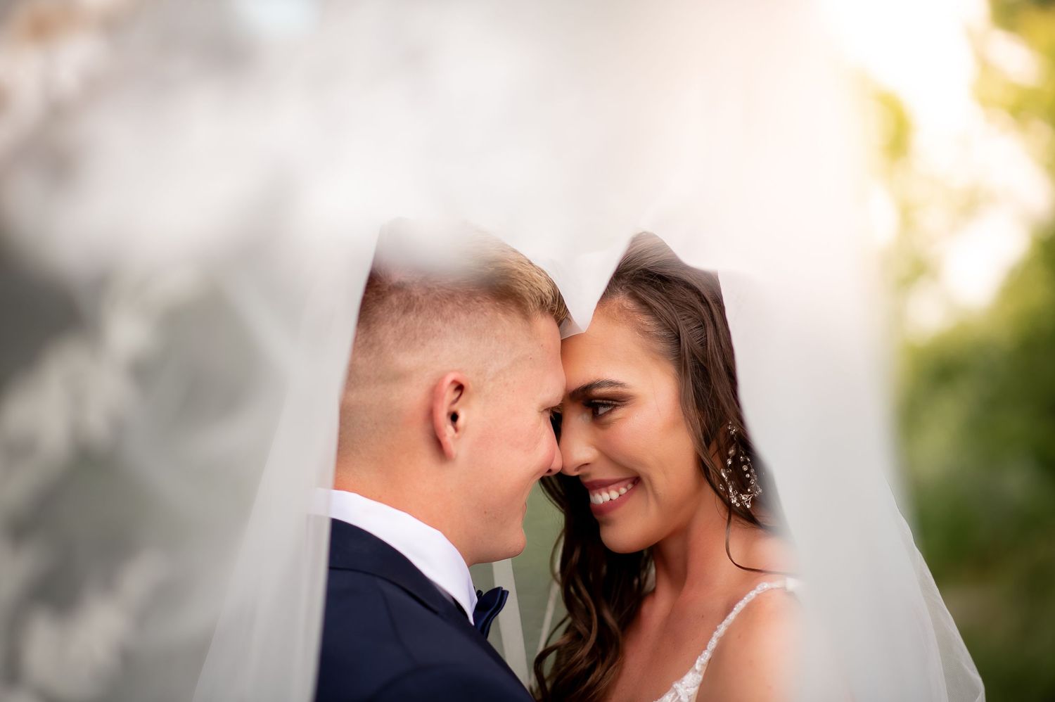 Intimate moment captured through delicate white wedding veil.