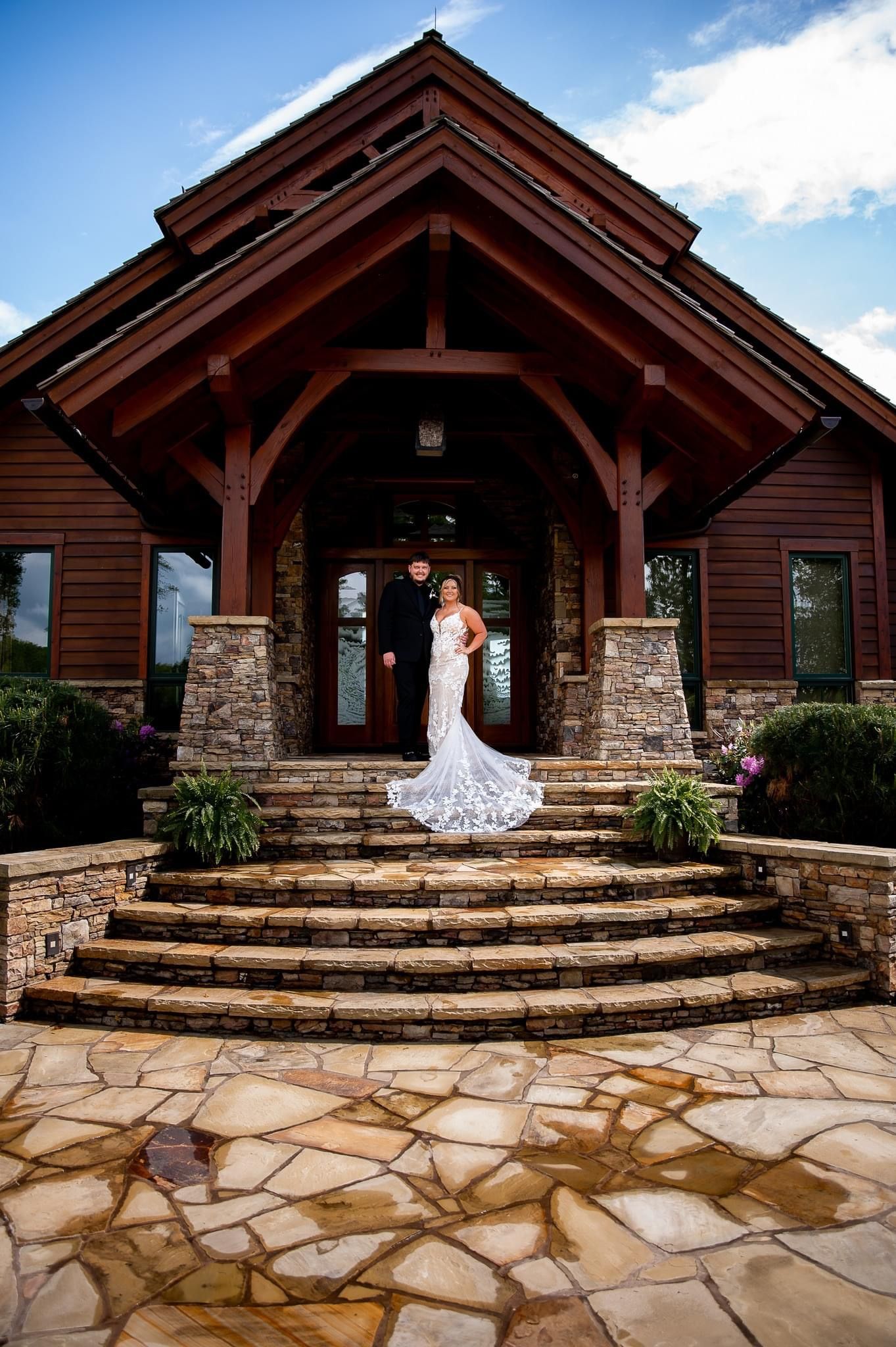 Rustic wooden lodge entrance with stone steps and white-dressed figure in elegant pose.