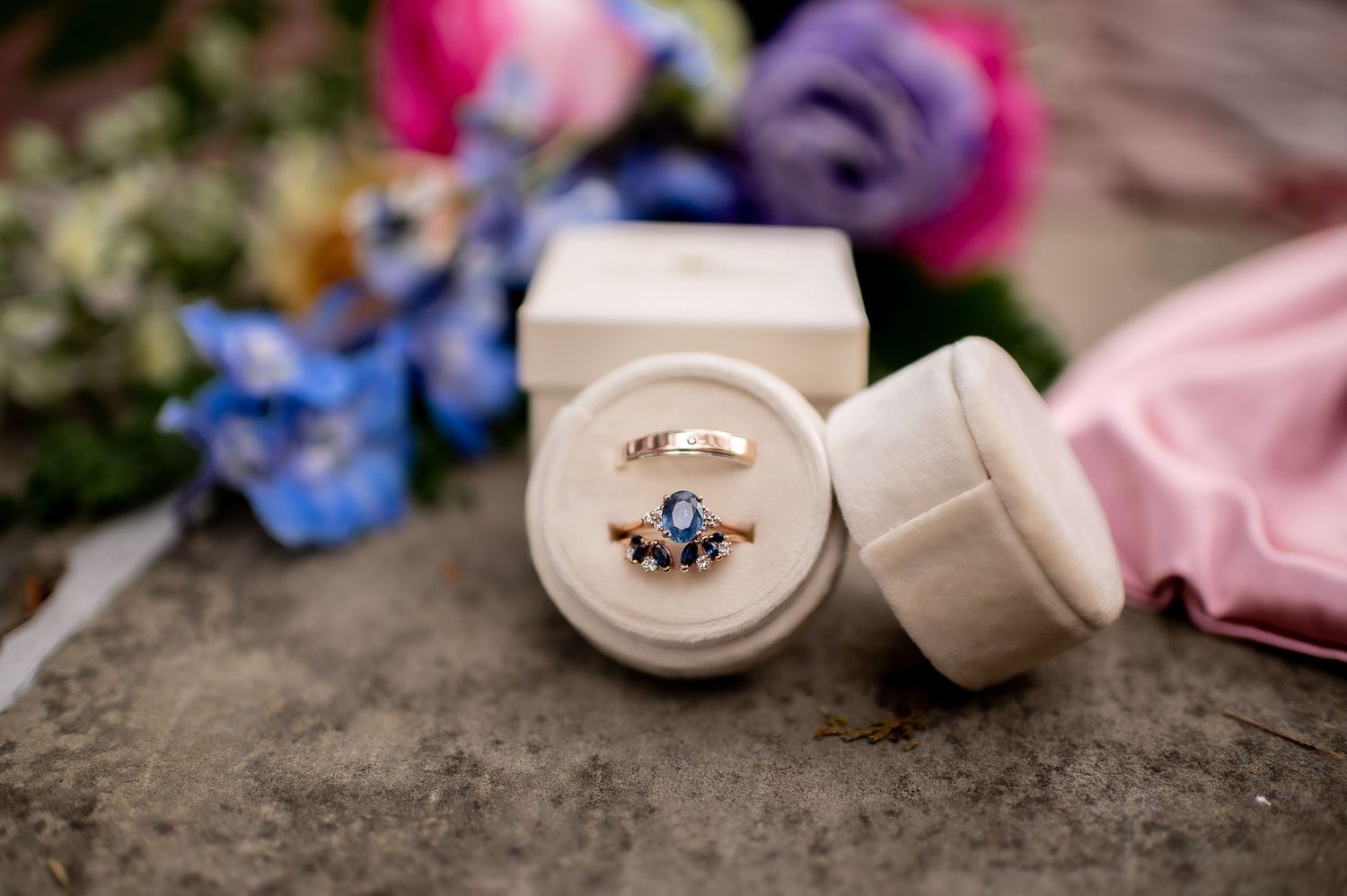 Elegant wedding rings and jewelry displayed on a textured surface with soft lighting.