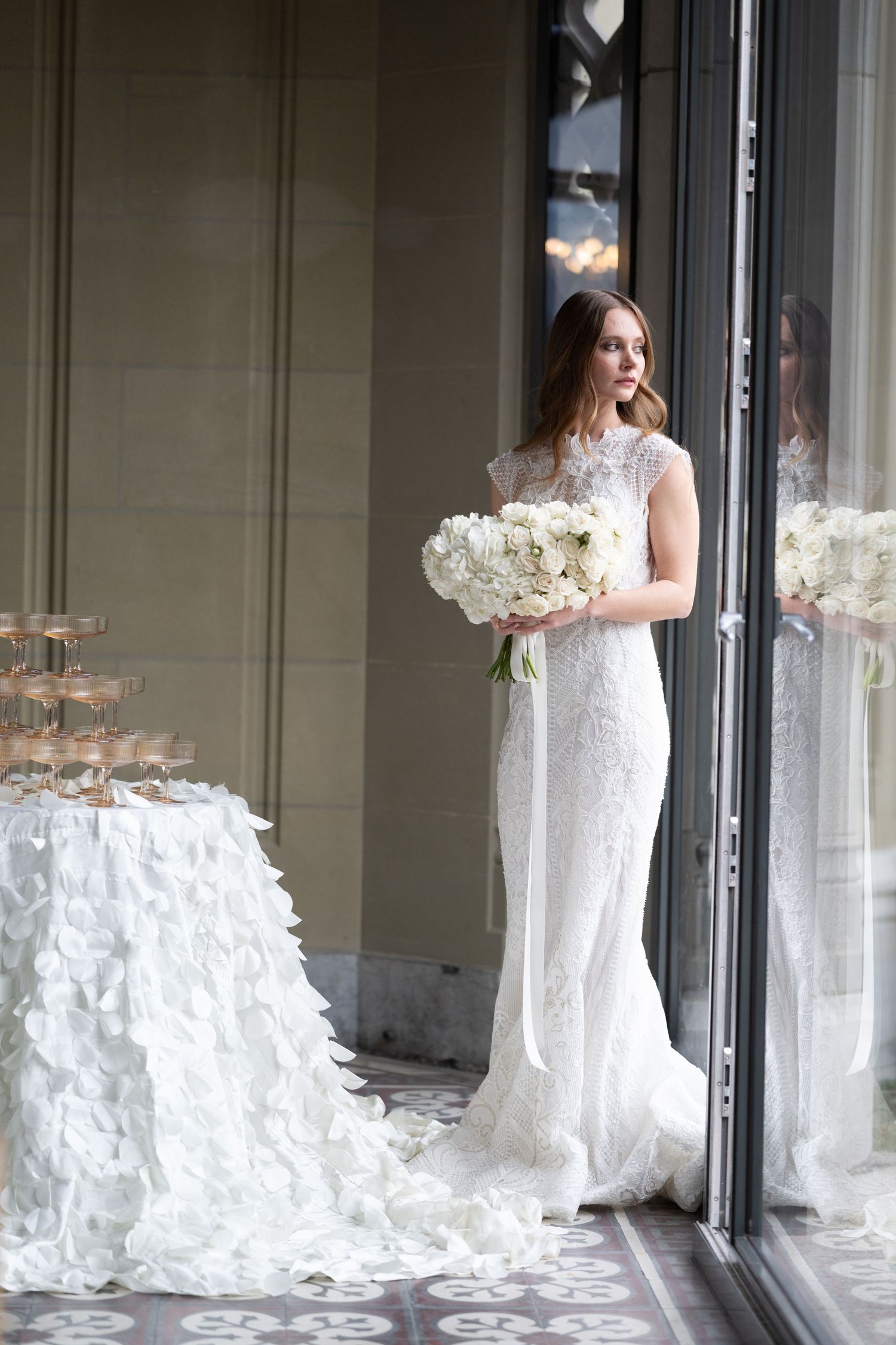 Foto von Frau mit Brautkleid, Braut, steht am Fenster, mit Brautstrauß in der Hand