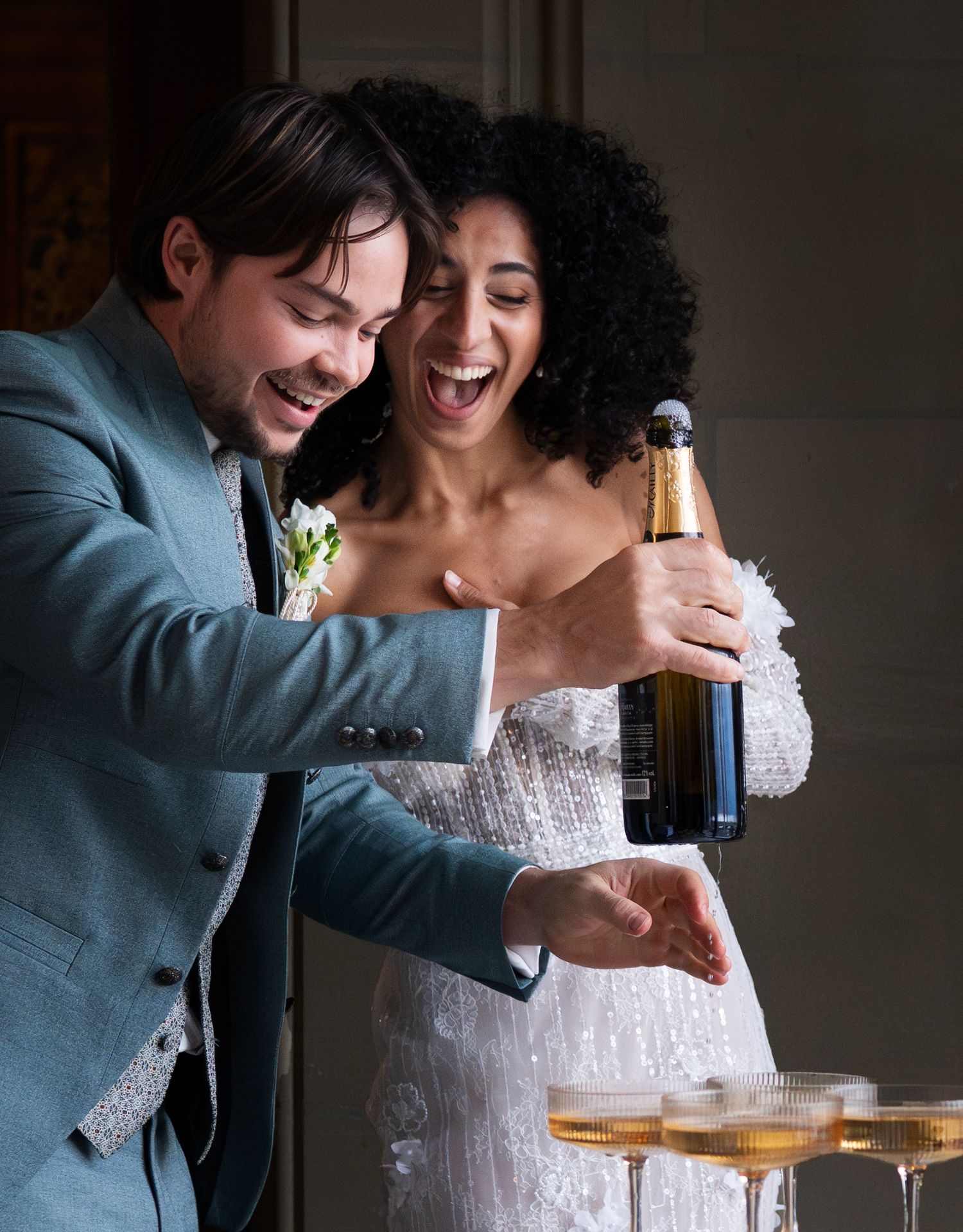 Foto von Braut und Bräutigam beim Sekt oder Champagner öffnen, lachen
