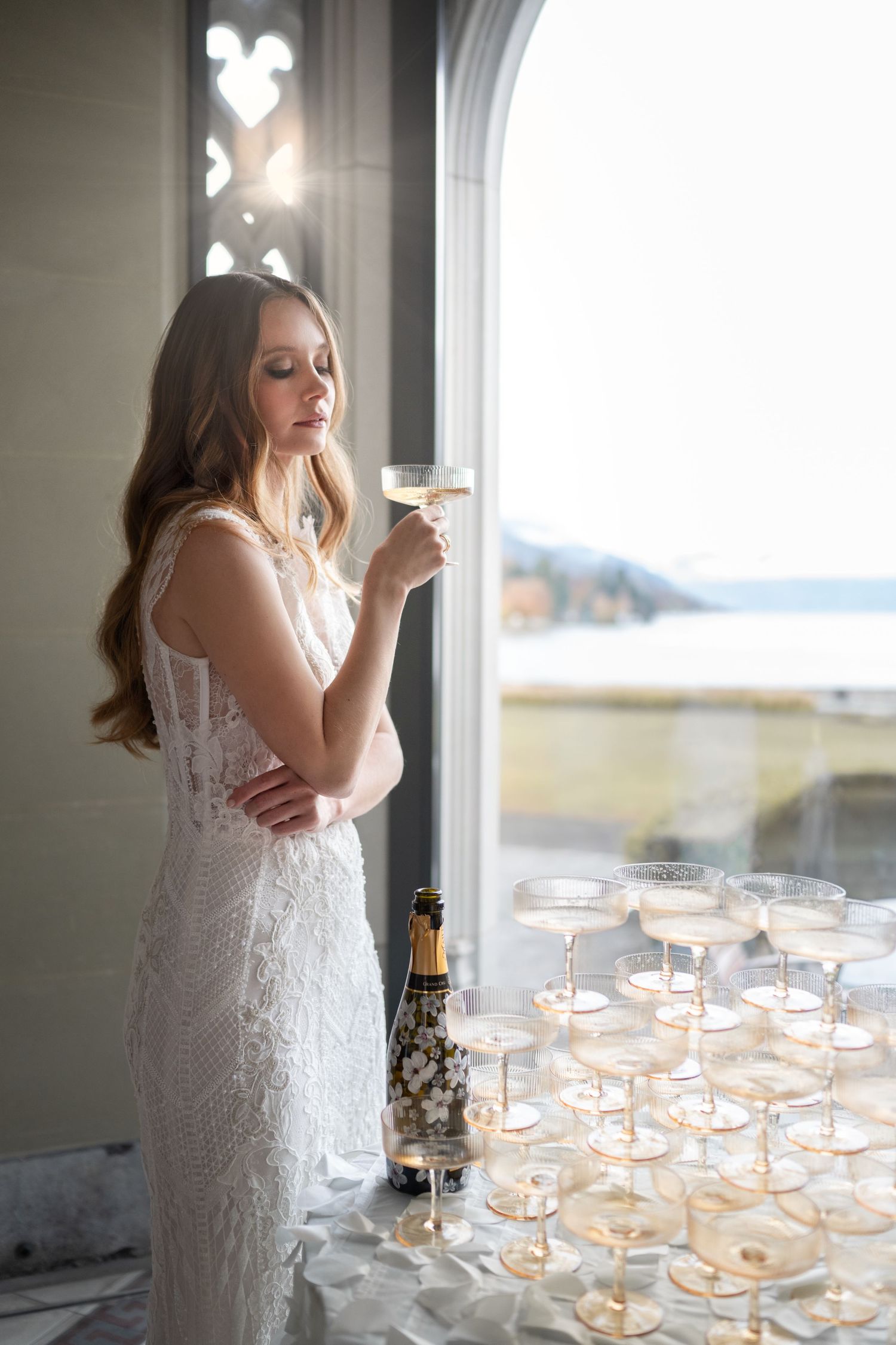 Foto von Frau mit Brautkleid, Braut, steht am Fenster, mit Brautstrauß in der Hand