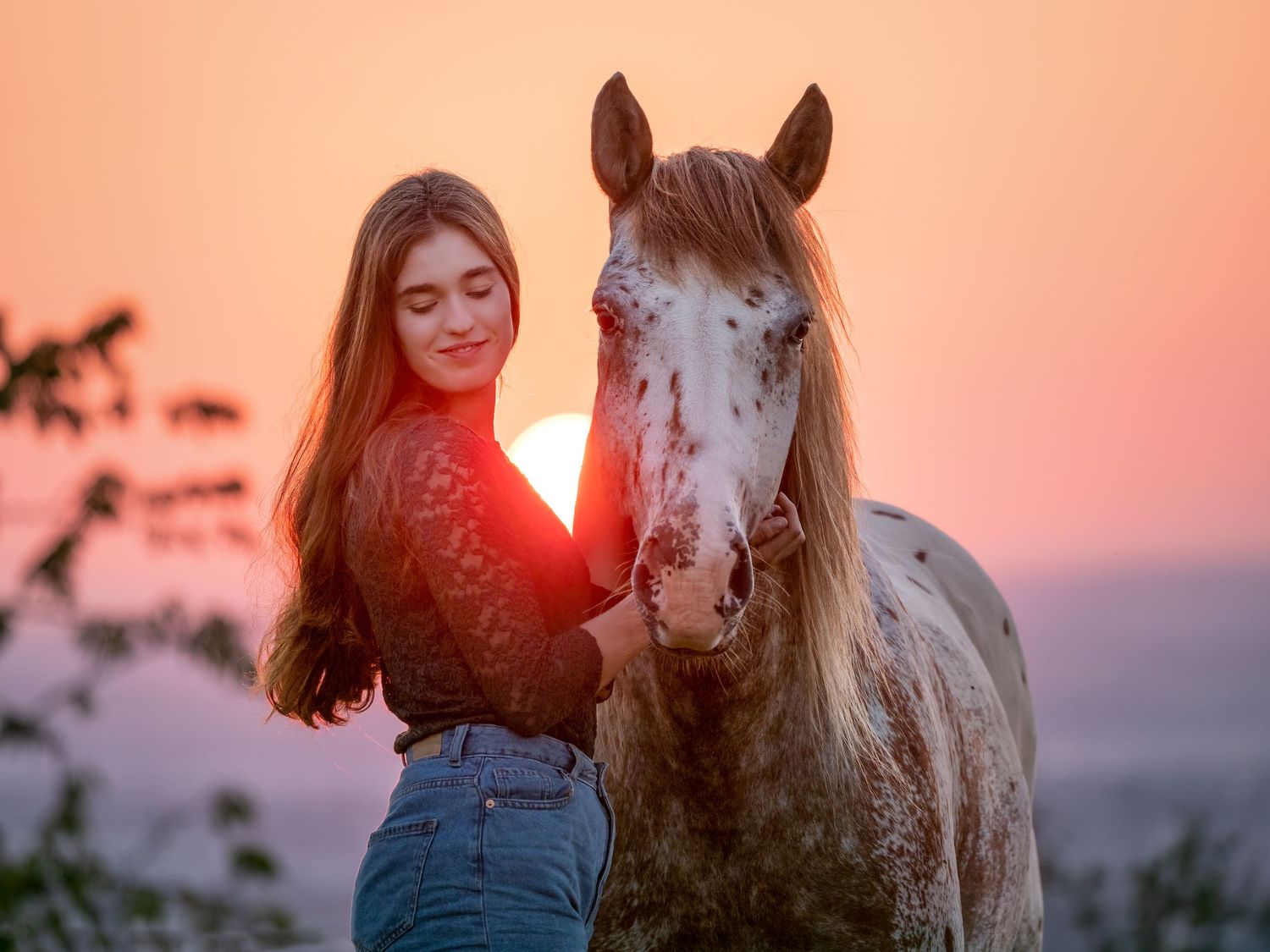 Frau und Pferd mit untergehender Sonne im Hintergrund