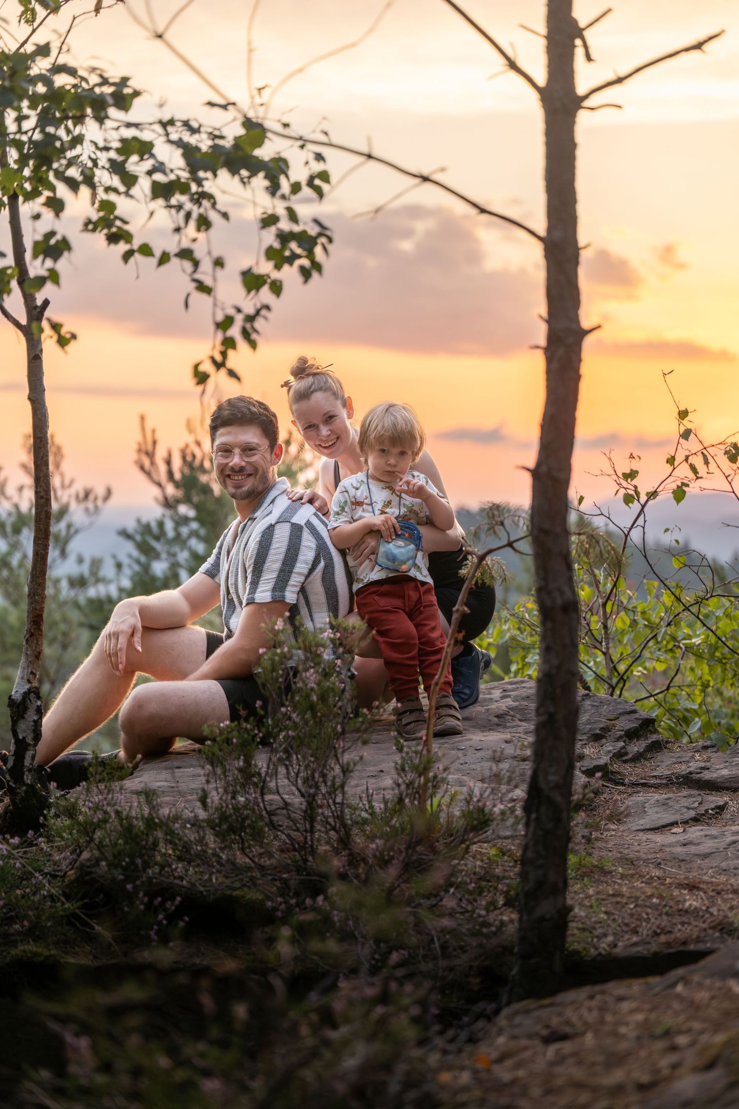Eltern mit Kind auf einem Felsen bei Sonnenutergang