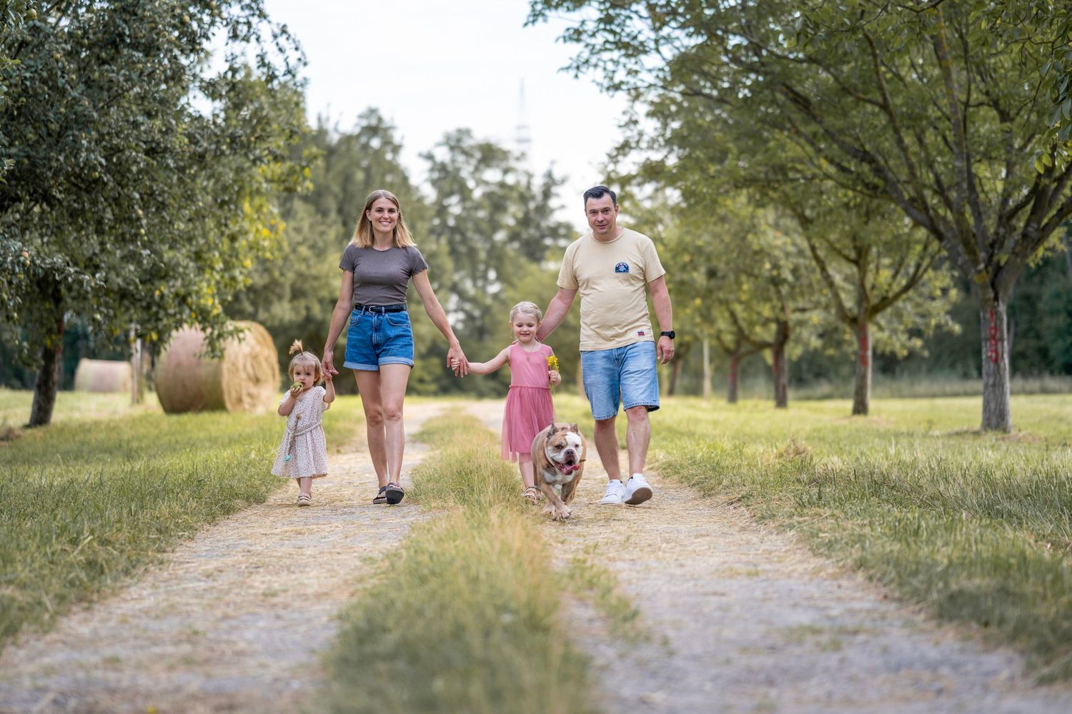 Eltern mit zwei Kindern laufen auf einem Feldweg
