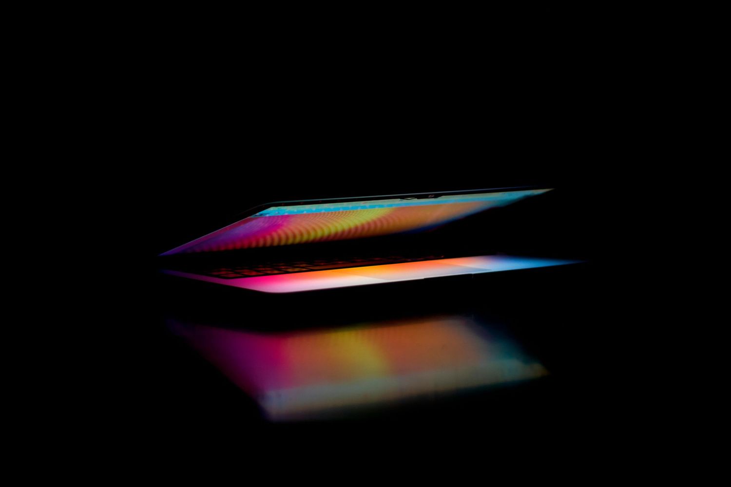 Moody close-up of a laptop opening with bold, colorful light—symbolizing bold brand strategy and creative storytelling at Dolce Vita Studio.