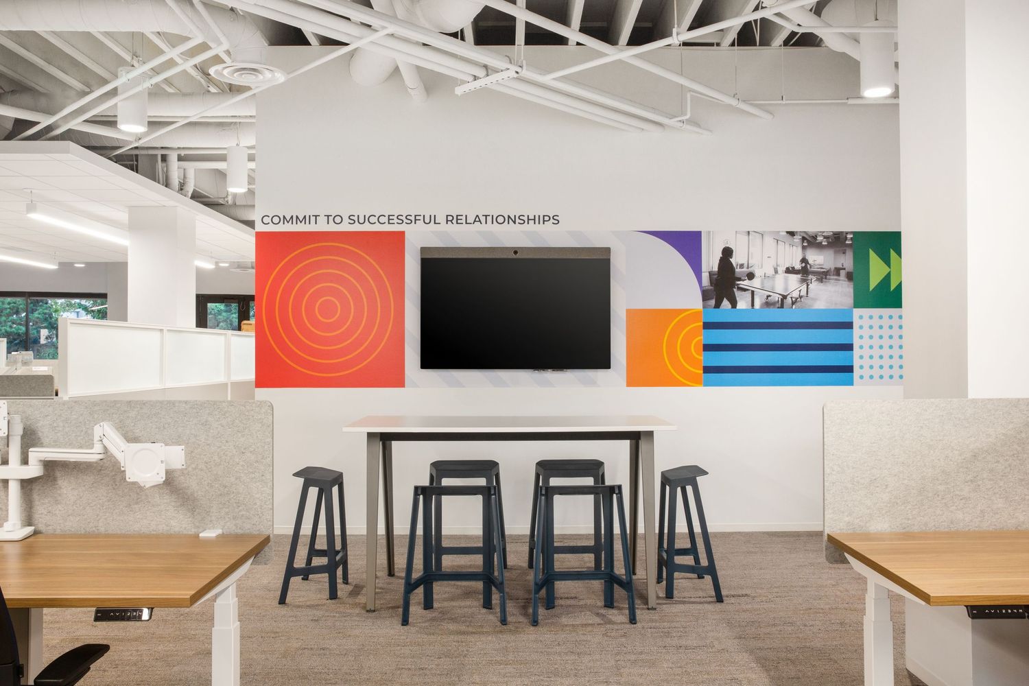 Open office common space in La Jolla business with bright geometric wall art and natural light, designed to foster teamwork and creativity.