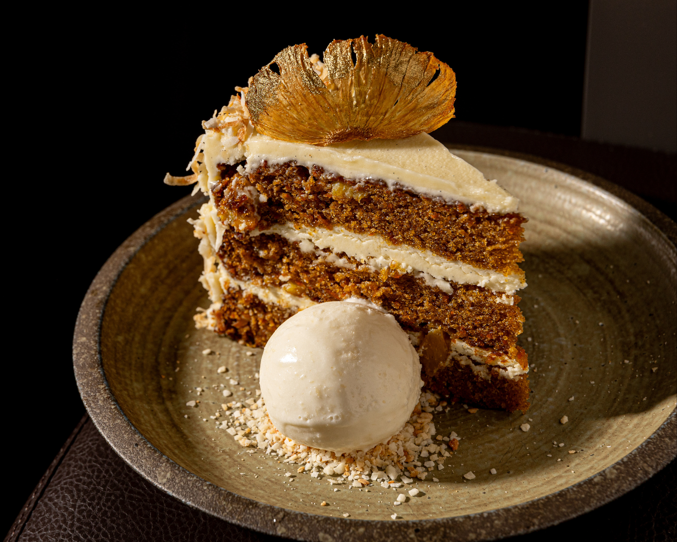Carrot cake dessert slices with cream cheese frosting and whipped cream on rustic plates.