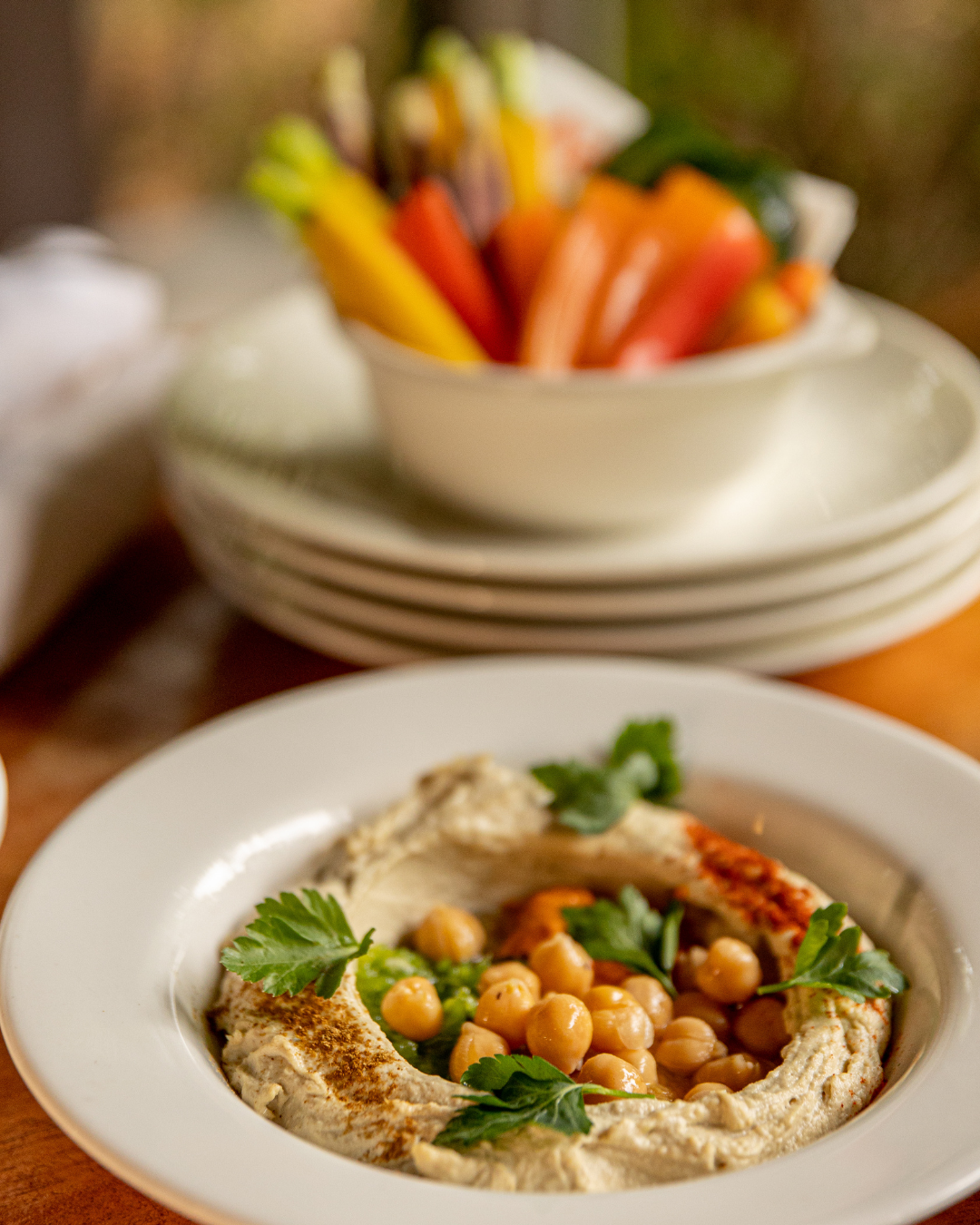 White plates of creamy hummus topped with chickpeas and herbs.