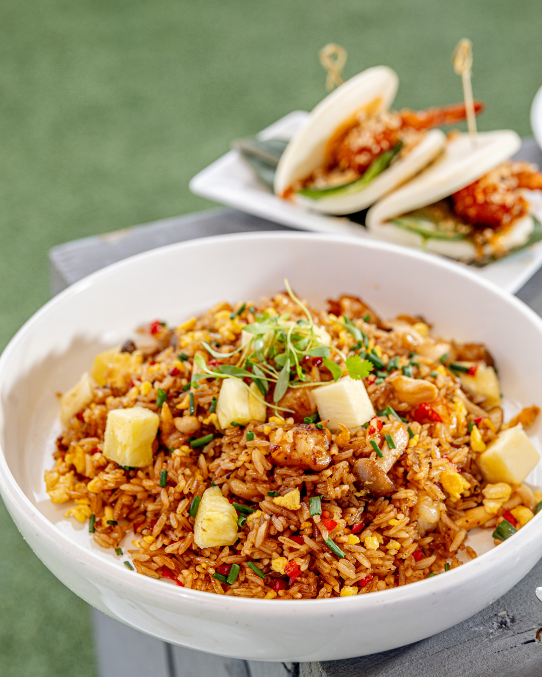 Large white bowl of fried rice with vegetables and tofu cubes served on a green surface.