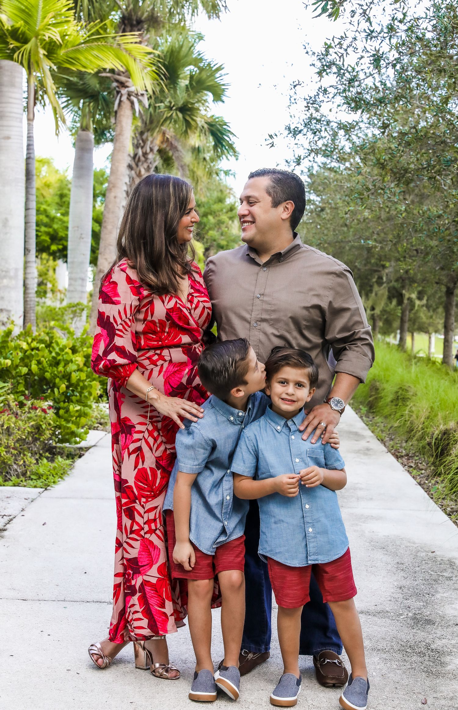 Family walking together on a palm-lined pathway in tropical setting.