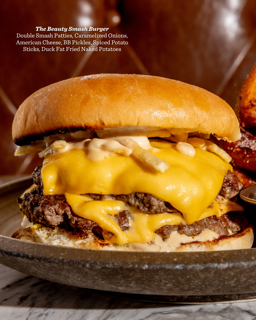 Juicy cheeseburger with melted American cheese on a toasted bun photographed in dramatic lighting.