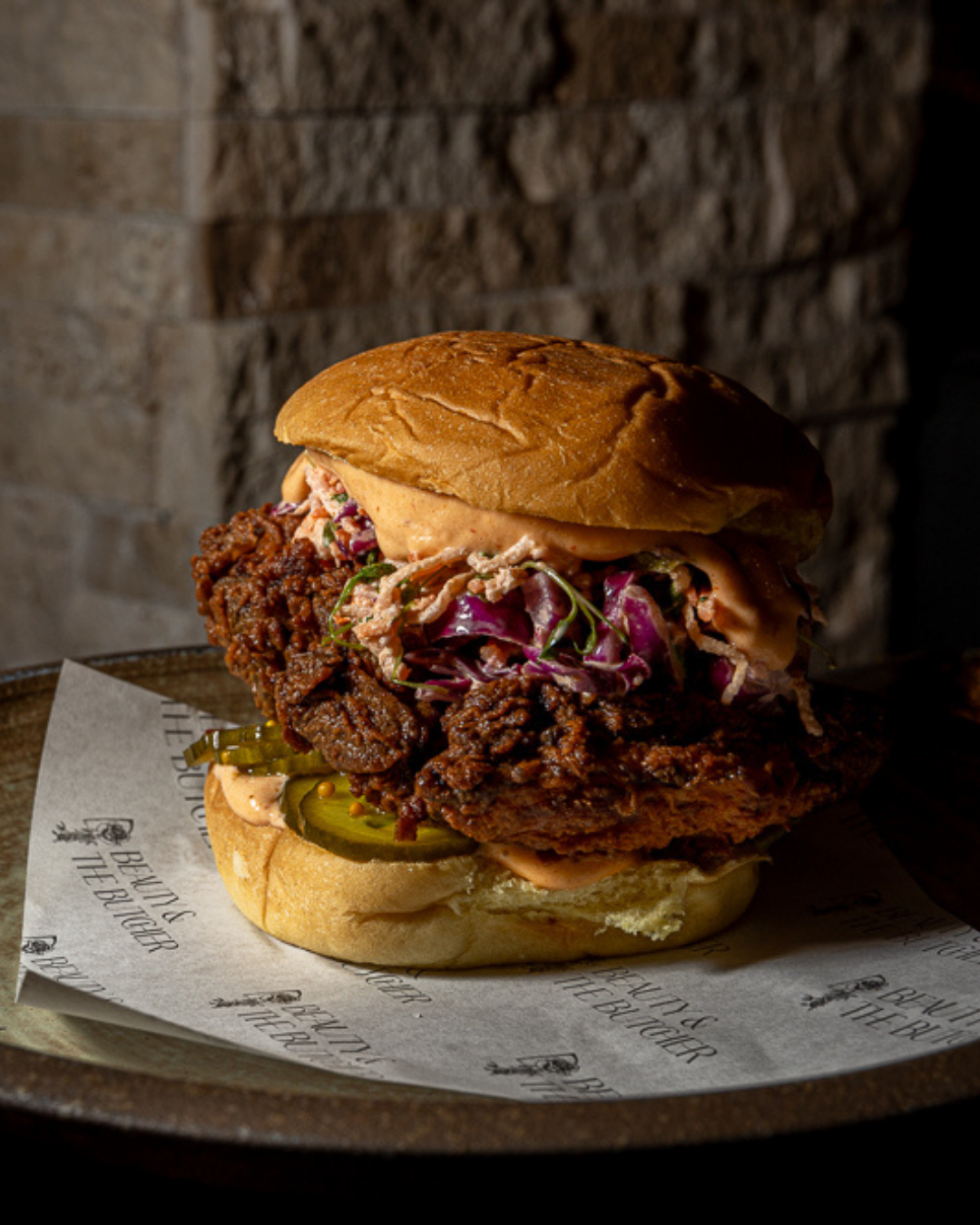 Gourmet fried chicken sandwich with pickles and purple slaw on a brioche bun.