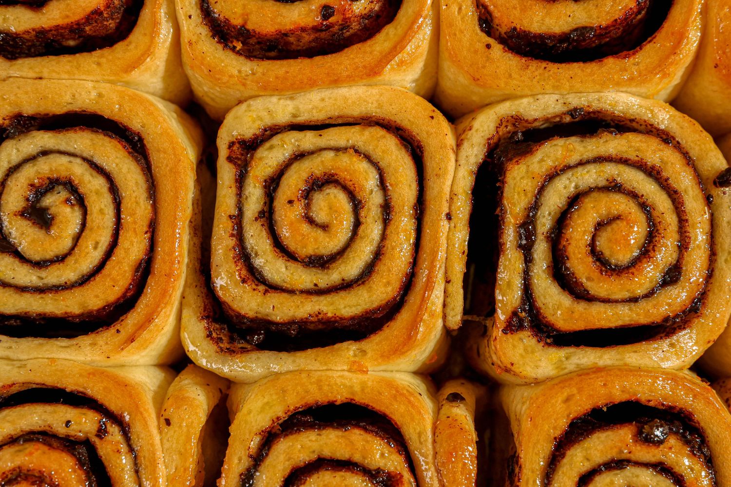 Close up of golden brown cinnamon rolls showing their signature spiral pattern.