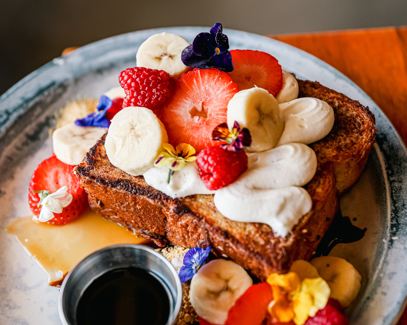 Beautifully plated dessert with fresh berries, bananas, and whipped cream.