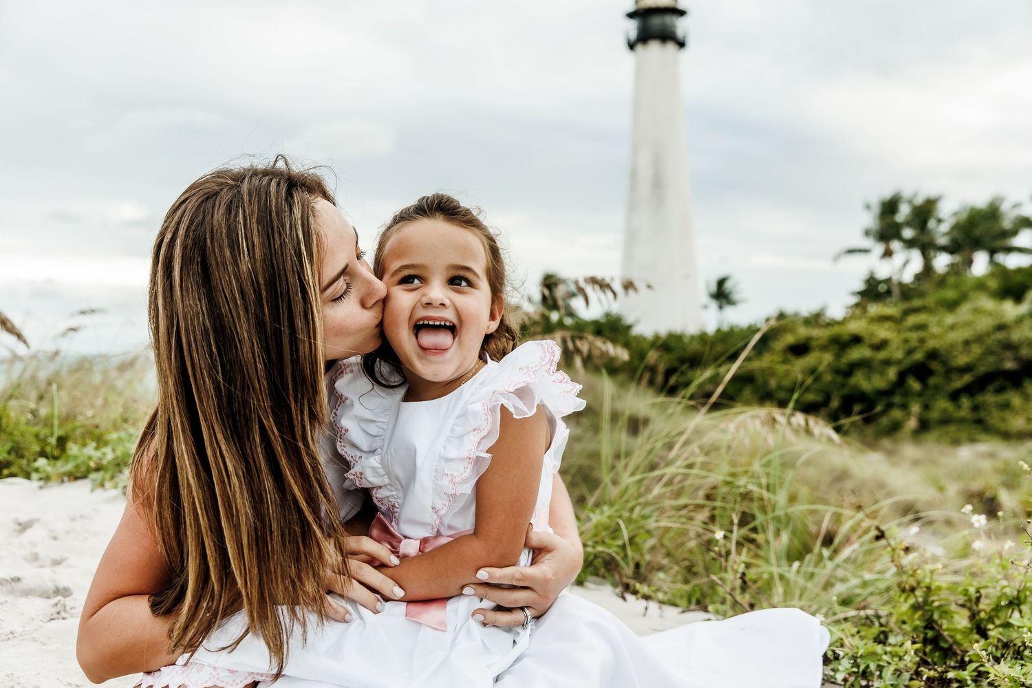 A joyful moment between parent and child with a lighthouse in the background.