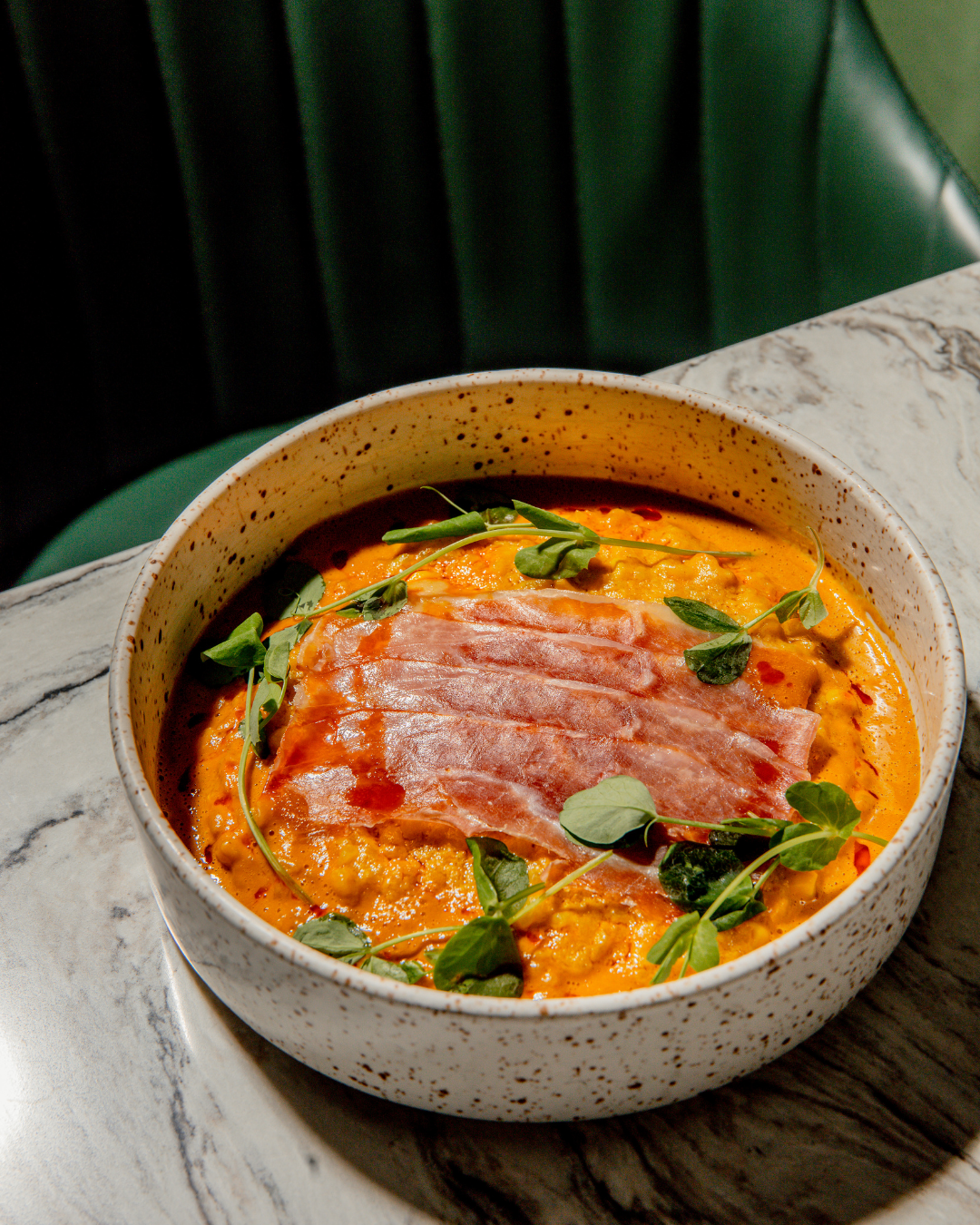Spicy curry soup with sliced meat and herbs in a ceramic bowl.