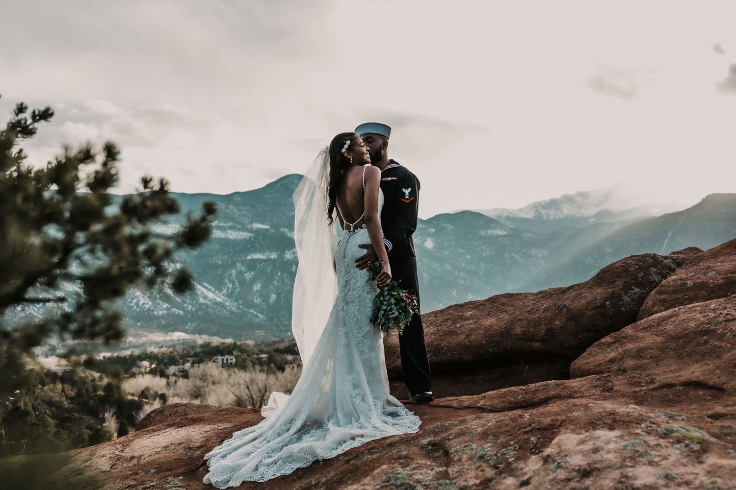 A romantic embrace between newlyweds on a mountain cliff with dramatic landscape views.
