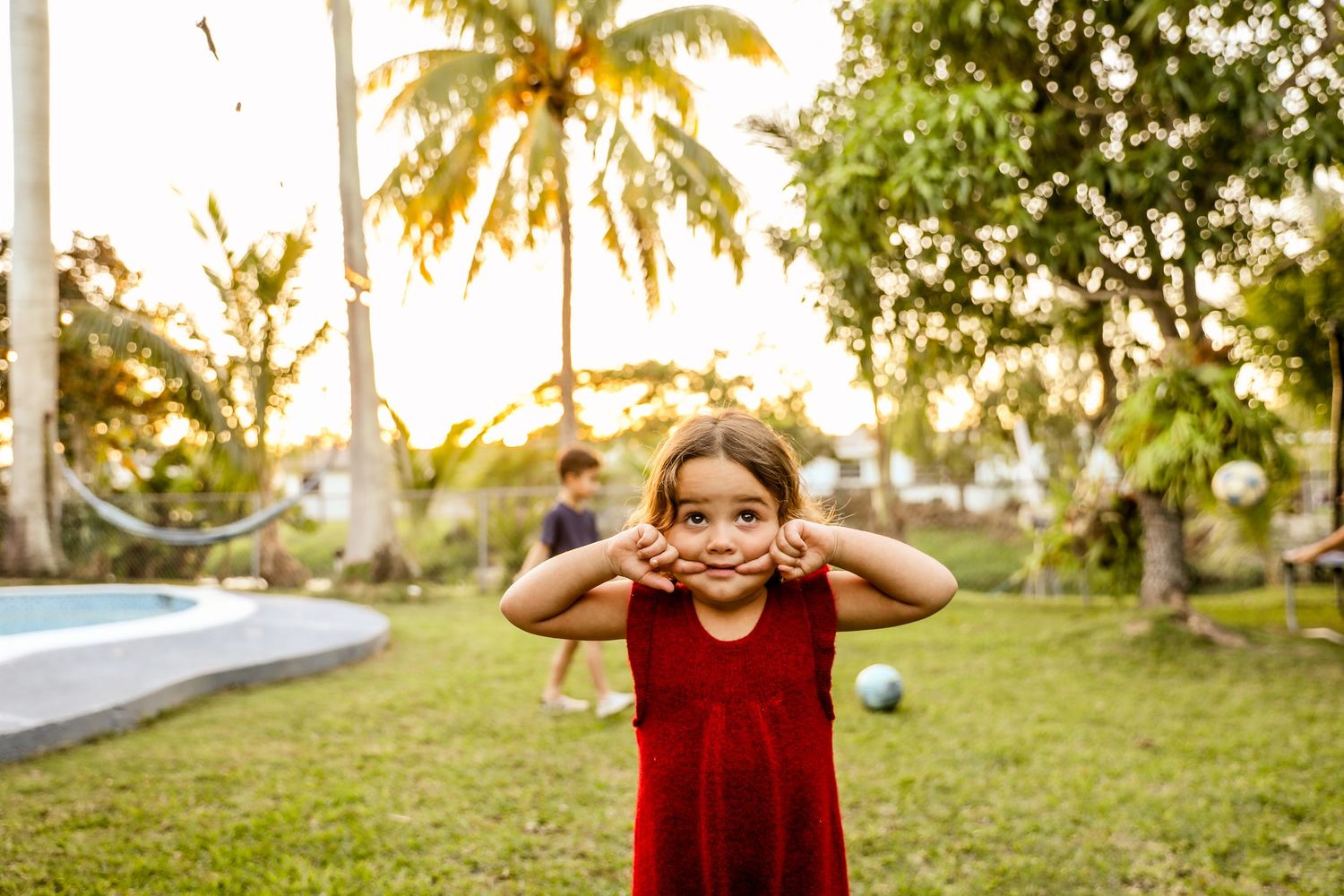 Children playing in a tropical garden setting with palm trees during golden hour.