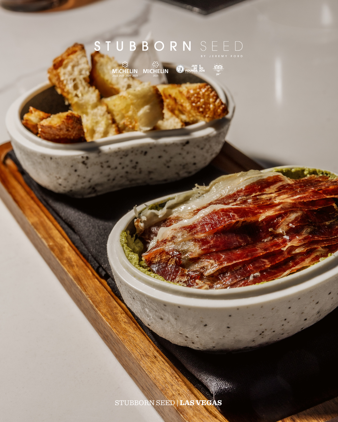 Rustic dining presentation with sliced meat and crusty bread served in speckled ceramic bowls.