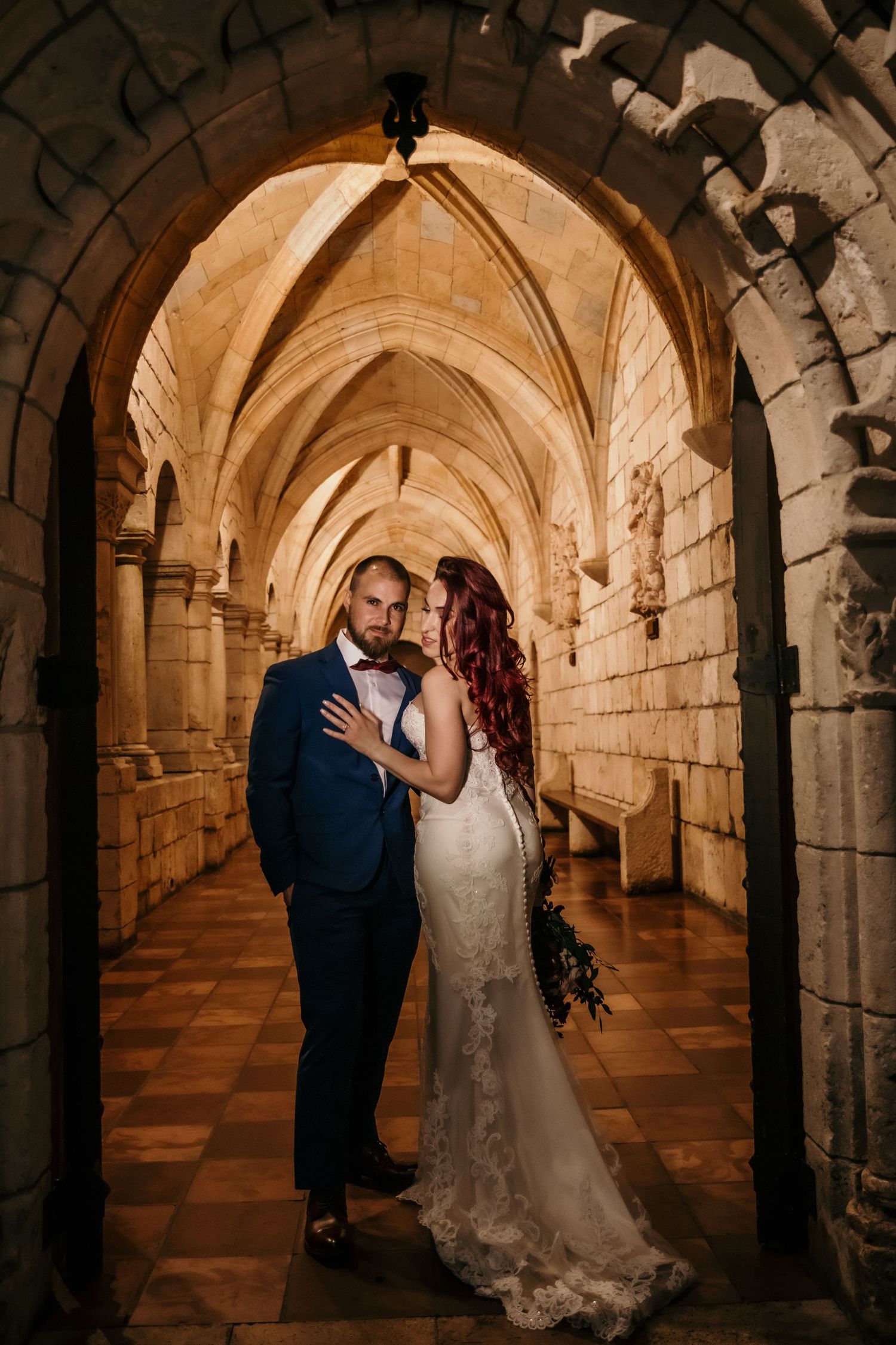 Elegant wedding photography session in a gothic stone cloister with vaulted ceilings.