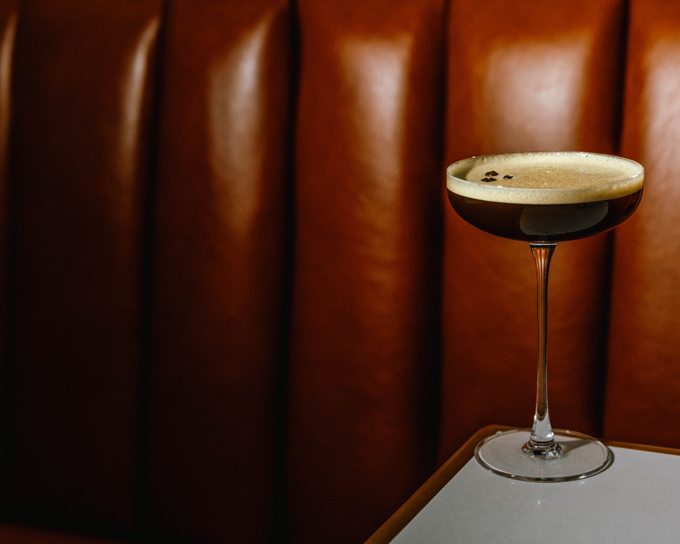 Moody cocktail lounge setting with backlit martini glasses on dark wood surfaces.
