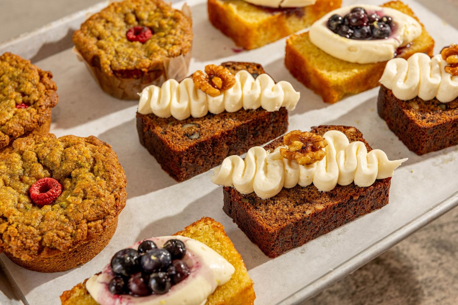 Assorted fresh baked desserts including cookies, brownies and pastries arranged on a white serving tray.