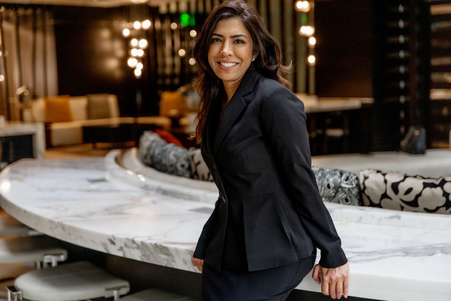 A person in a black suit jacket inspects white mattresses in a furniture showroom.