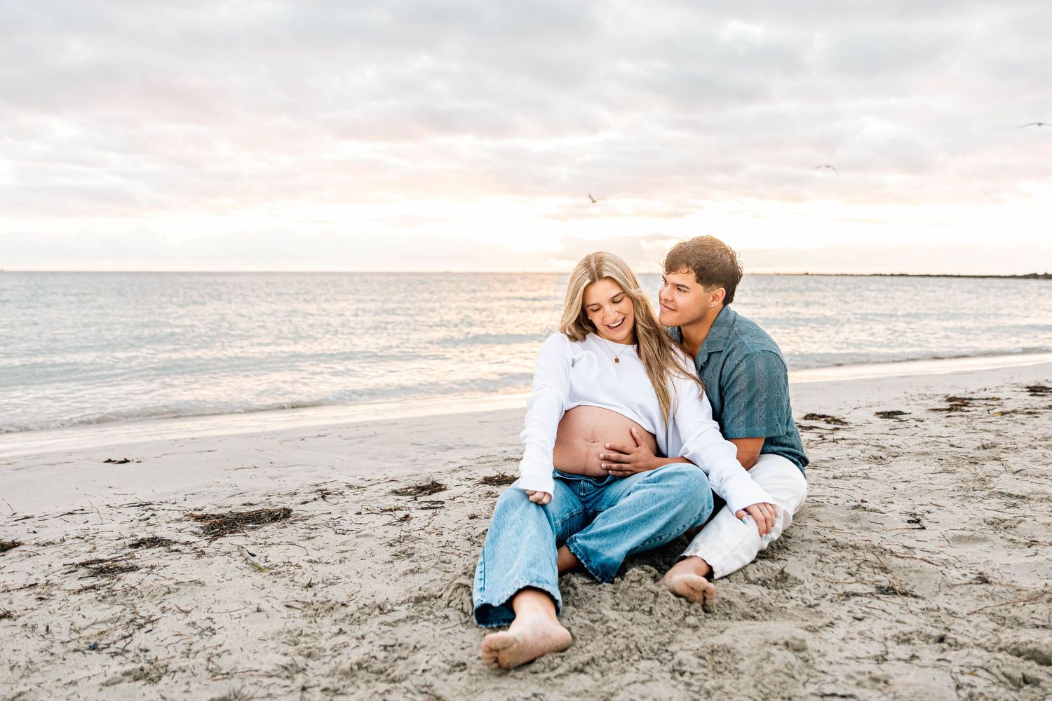 A joyful maternity portrait session on the beach at sunset.