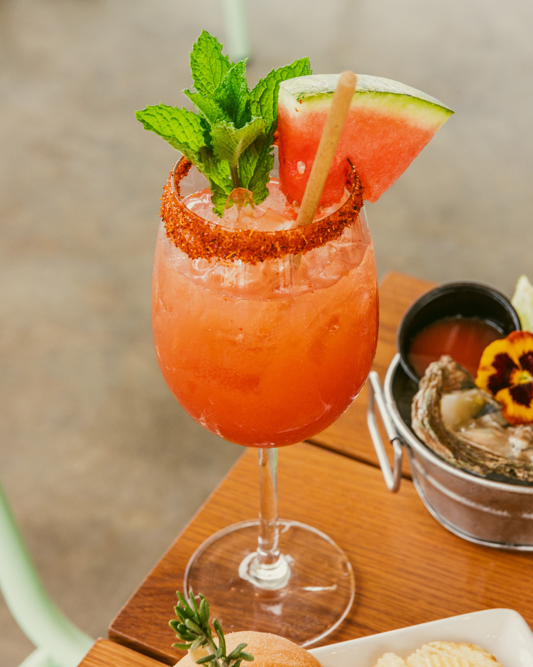 Vibrant orange cocktails garnished with mint leaves and salt rims served in stemmed glasses.