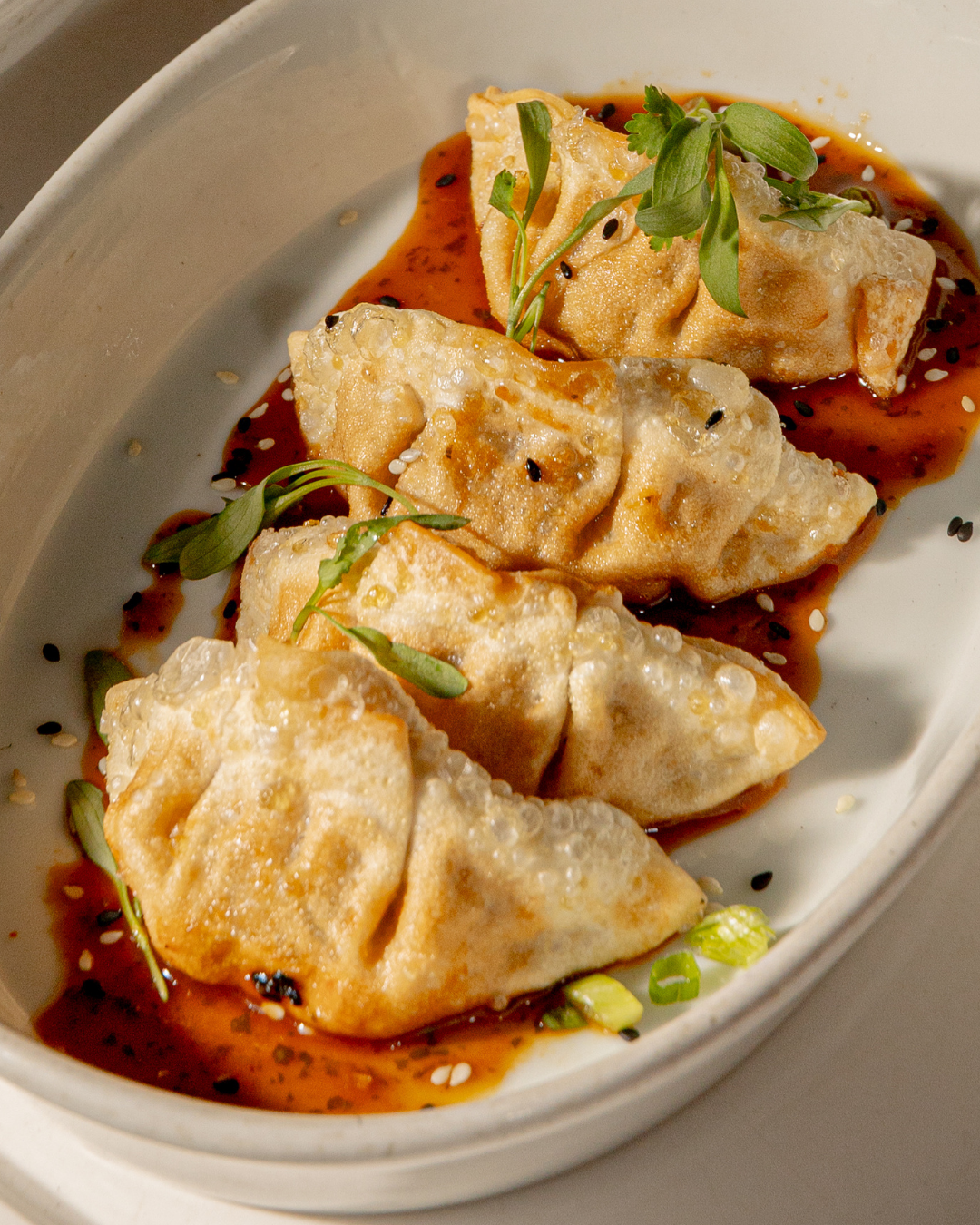 Steamed dumplings drizzled with chili oil and garnished with fresh herbs.