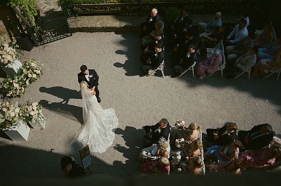 Aerial view of bride and groom sharing first dance at outdoor wedding ceremony surrounded by seated guests.