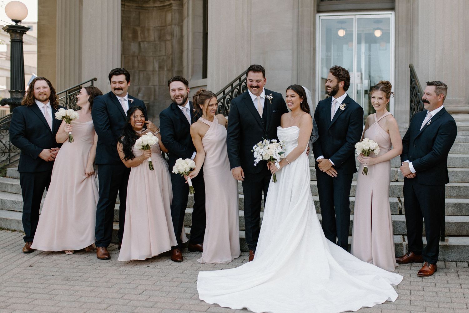 Formal wedding party posed in front of classical stone columns in Waukesha, WI