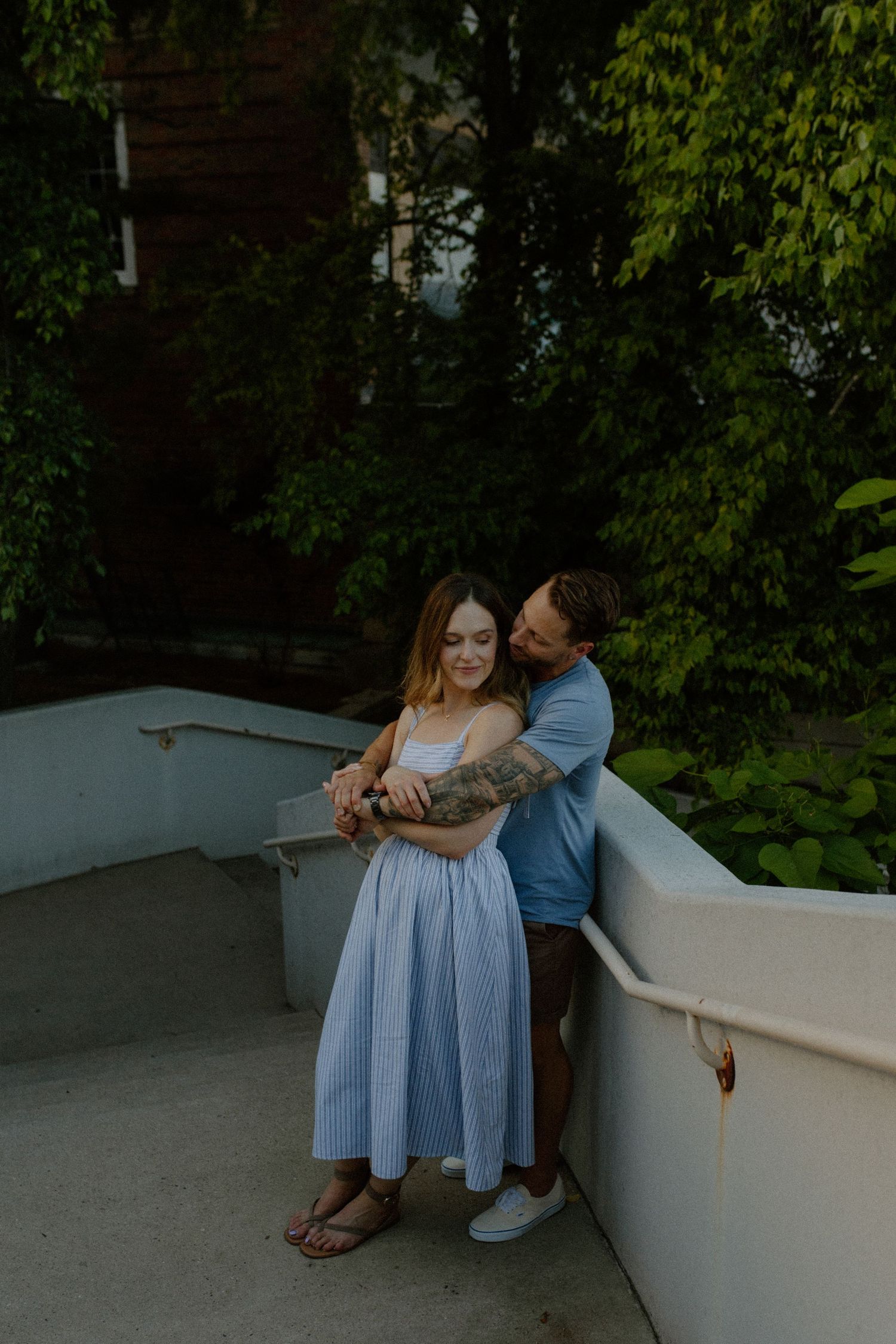 Intimate moment captured on white concrete steps with green plants in background in Madison, WI couples photography session