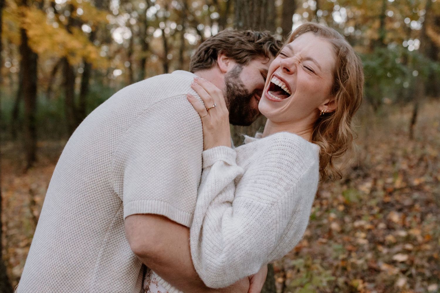 A couple shares a joyful moment dancing together in an autumn forest setting at Lapham Peak engagement session