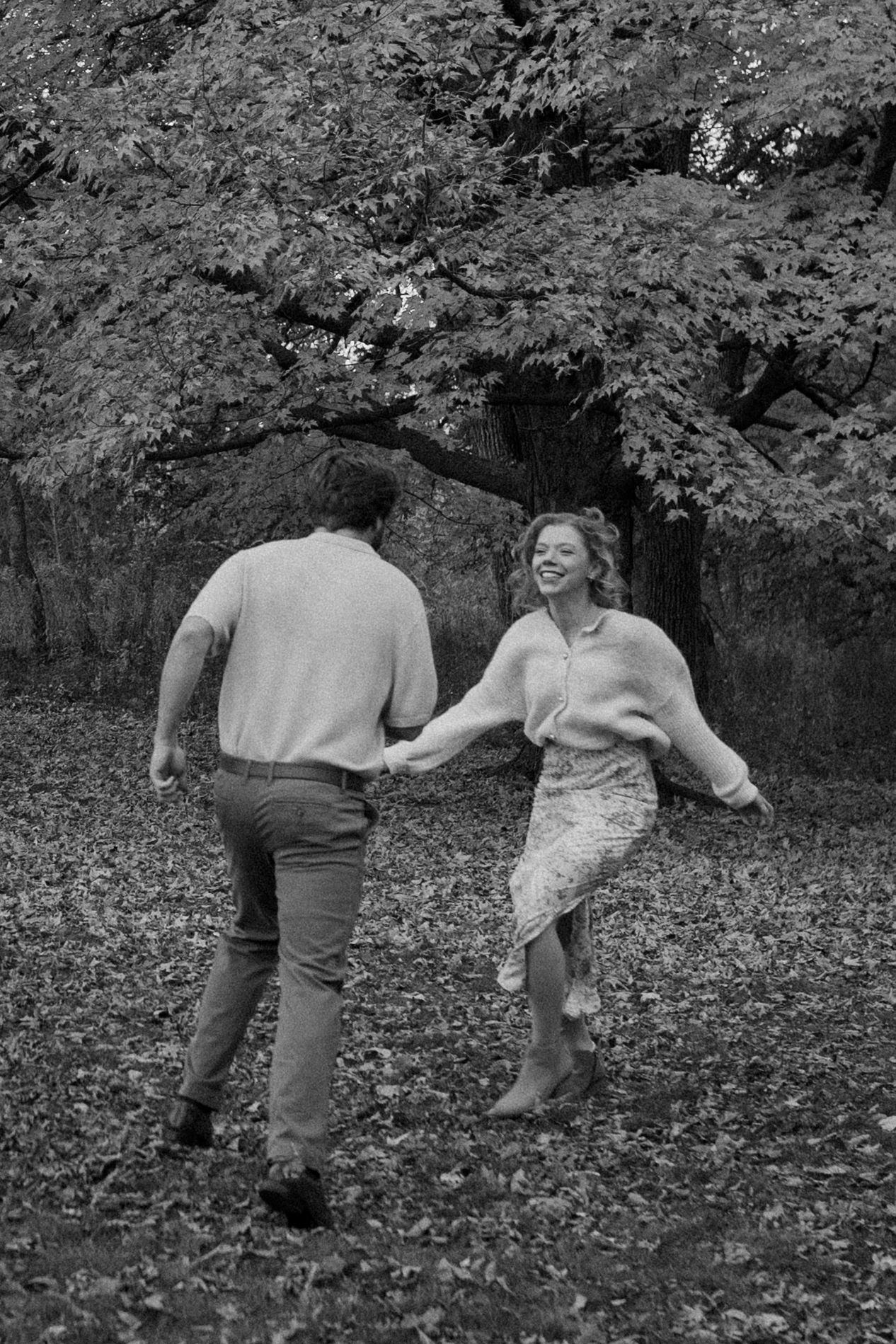 A couple dances together on fallen leaves in a monochrome forest scene at Lapham Peak engagement session