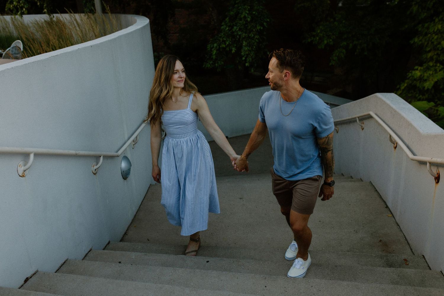 Two people hold hands while walking down outdoor steps in Madison, WI for outdoor couples photography session