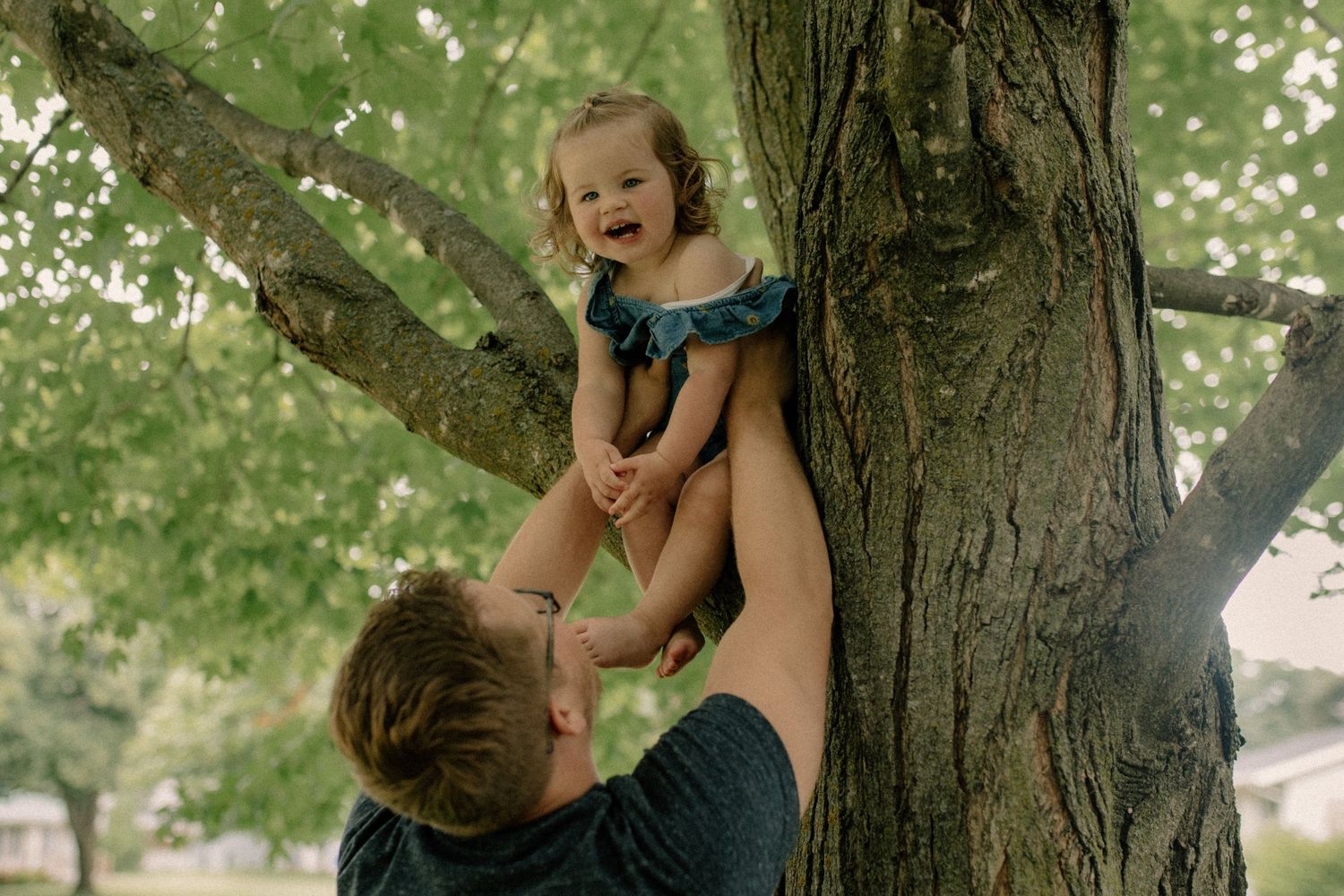 Playful family interactions under the shade of large green trees for candid family photos