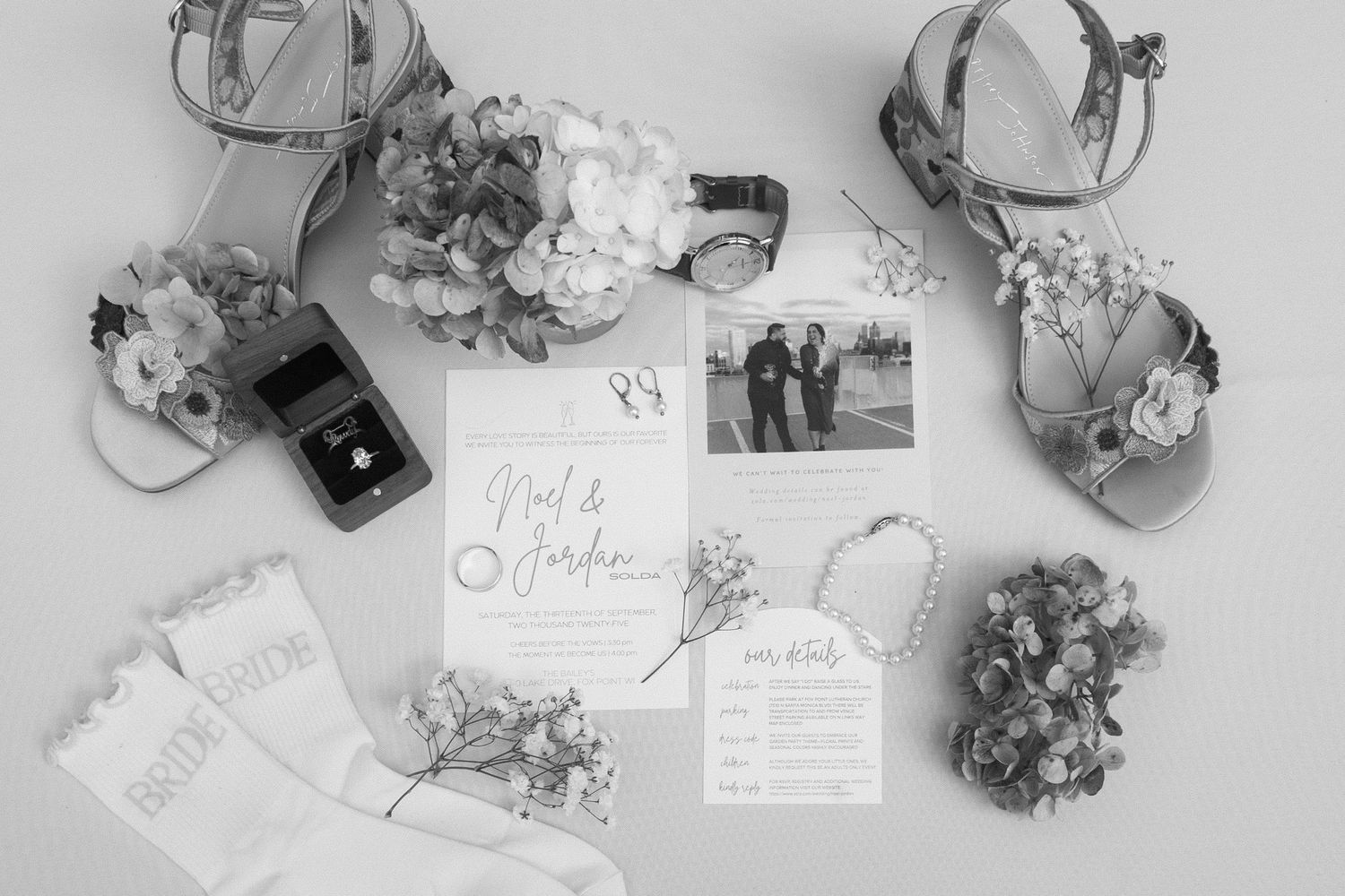 Black and white flat lay of wedding details including rings, flowers, and stationery for Wisconsin garden wedding